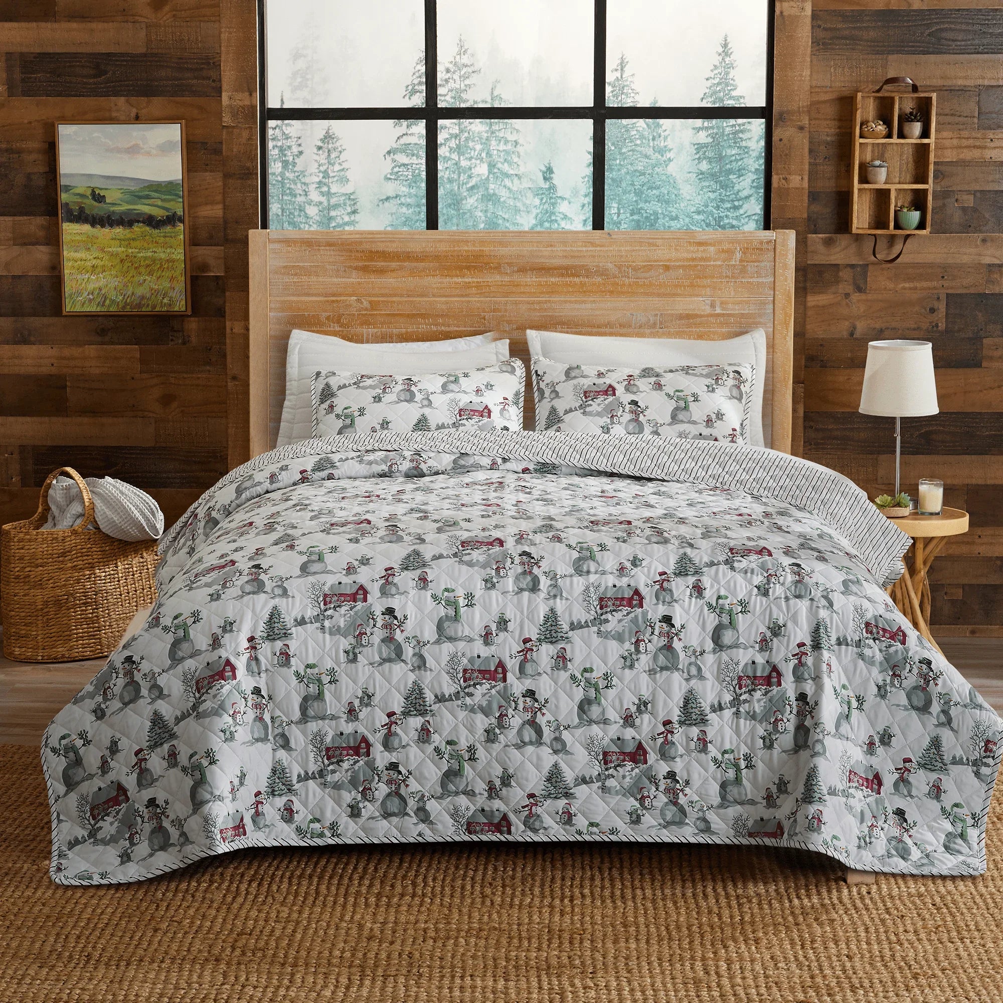 Bedding set with winter-themed design on a bed in a room with wooden walls and a window.
