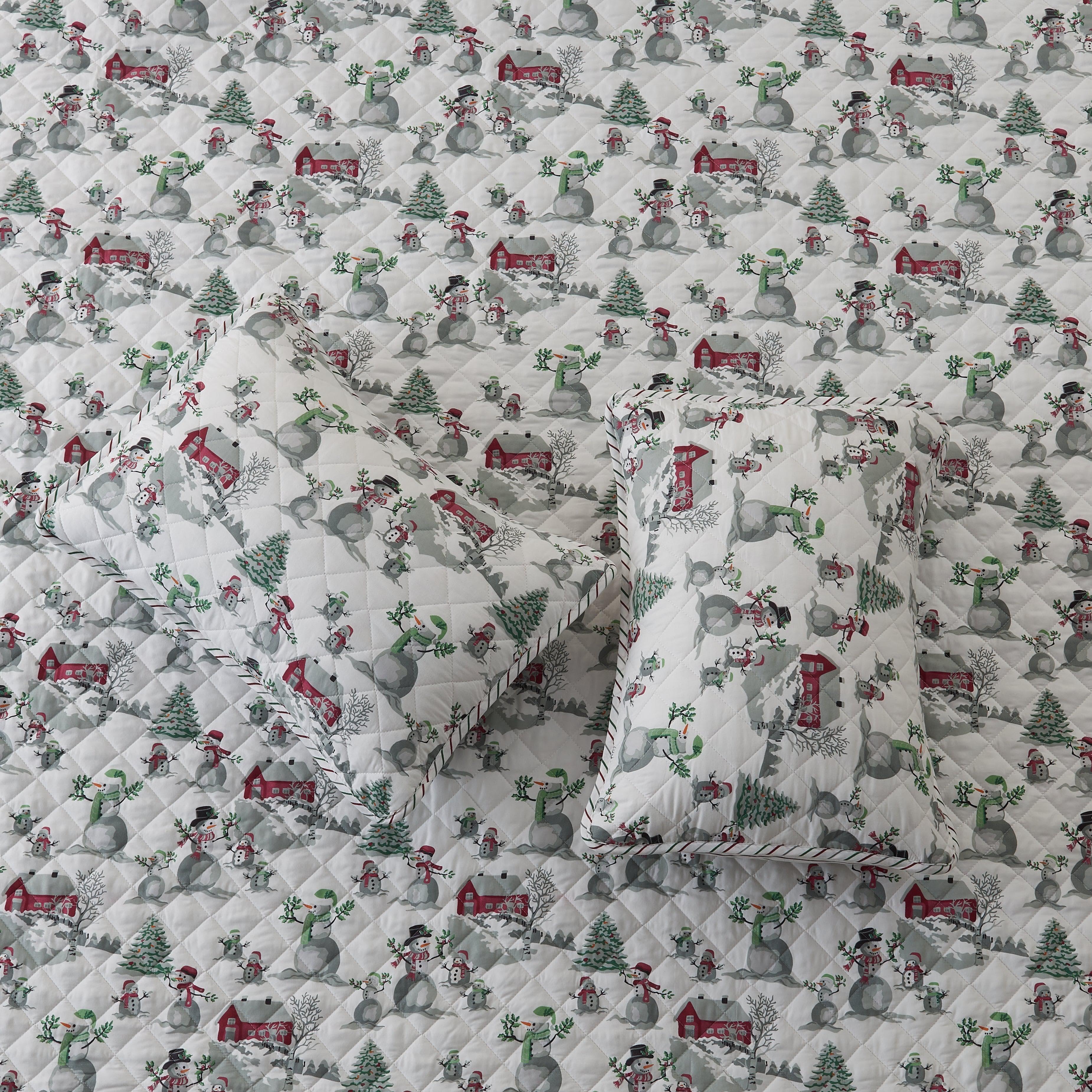 Quilt with Christmas-themed fabric featuring snowmen, trees, and houses.