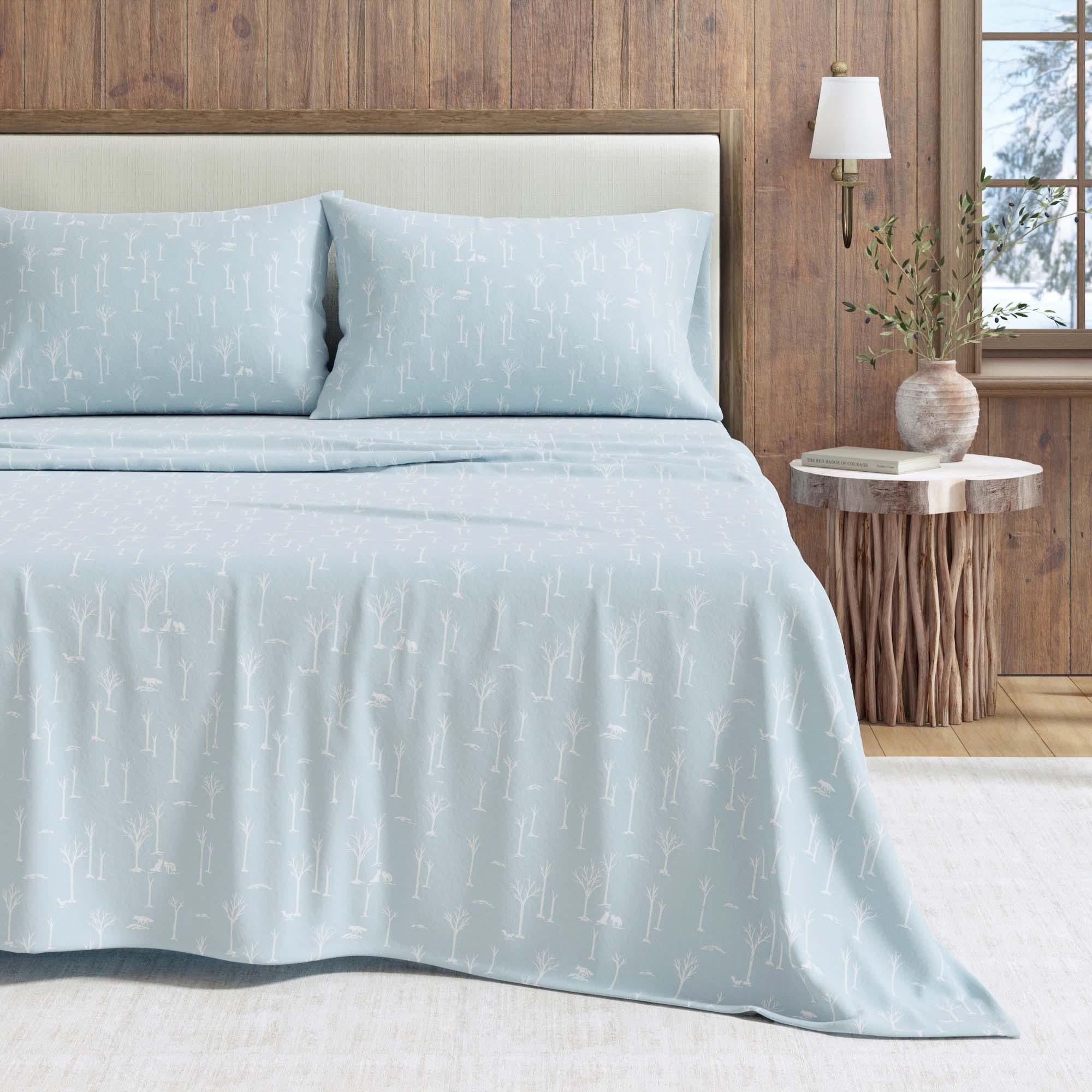 Light blue bedding set on a bed with a wooden headboard and side table in a room.