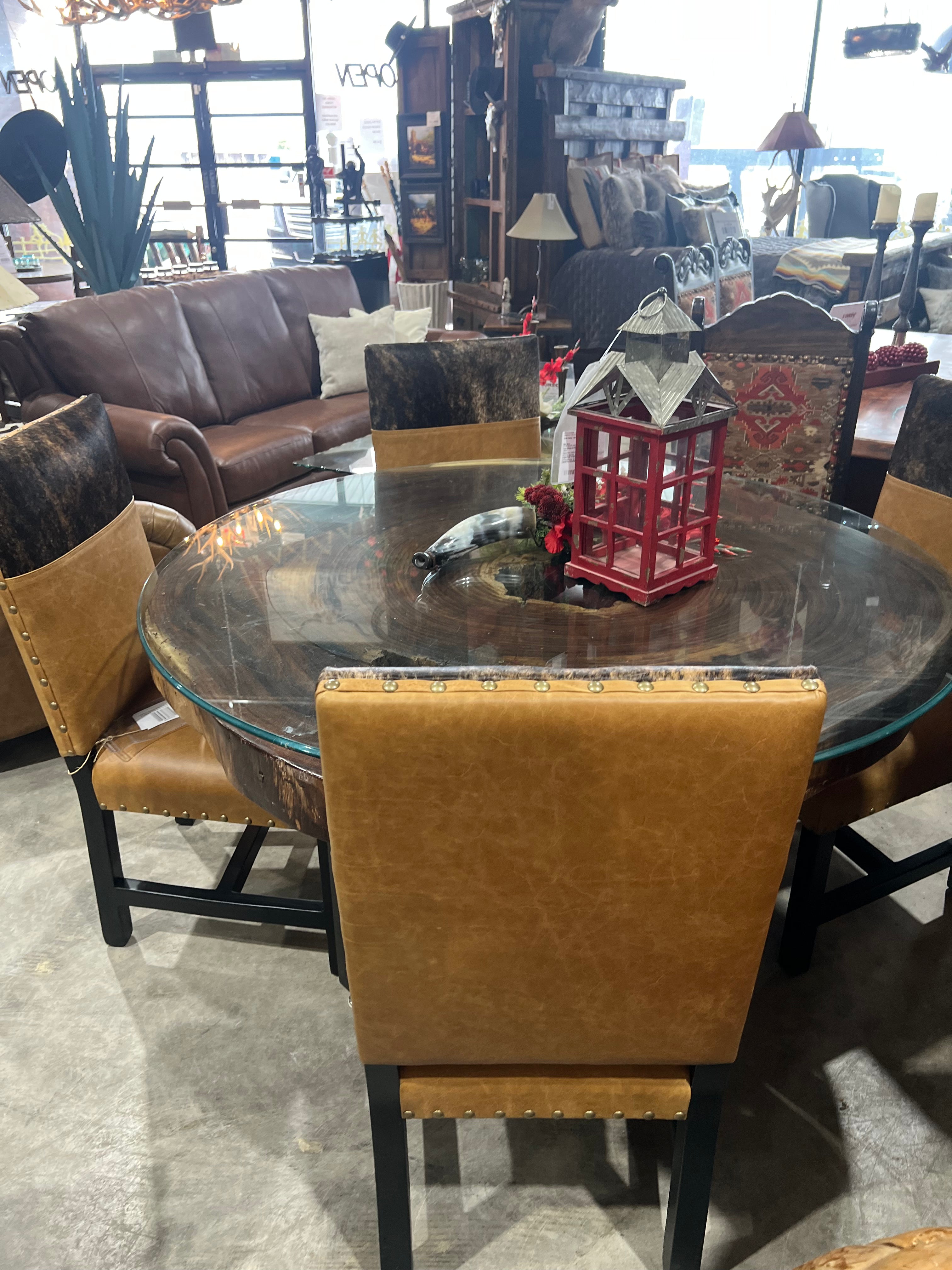 Dining table with glass top and brown chairs in a furniture store setting - Your Western Decor