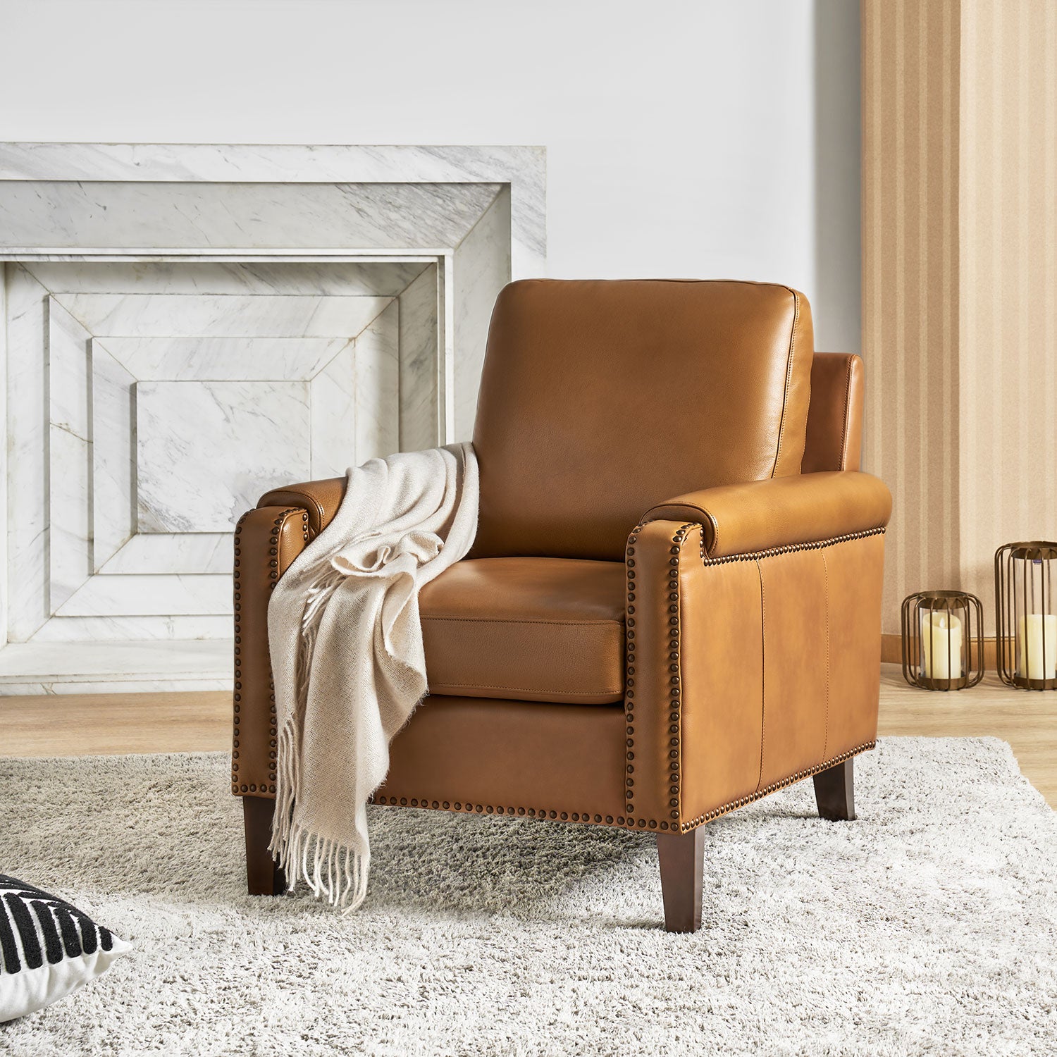 Carson Camel leather accent chair with nailhead trim styled in a bright living room with fireplace and neutral decor