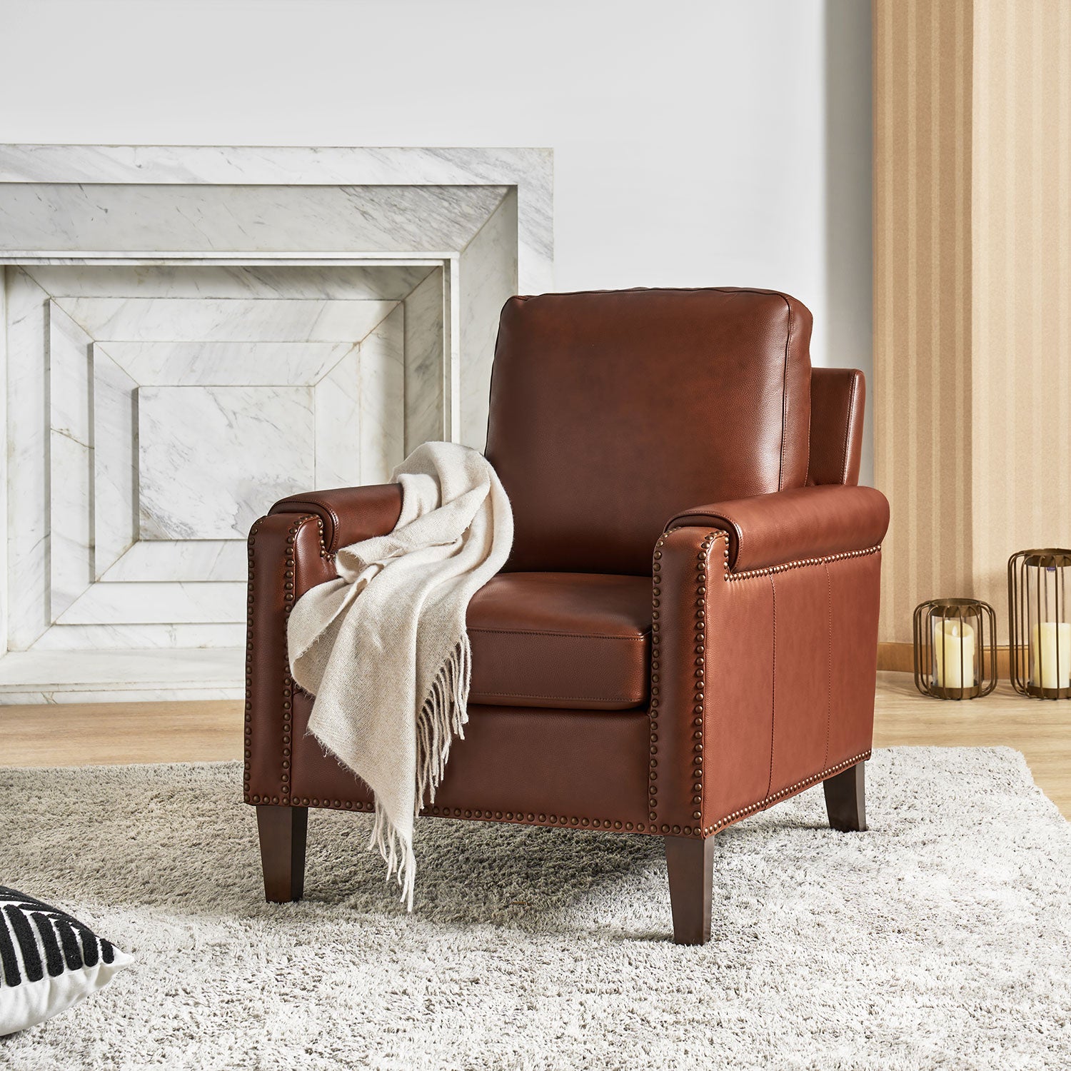 Carson Brown leather accent chair with nailhead trim styled in a bright living room with fireplace and neutral decor
