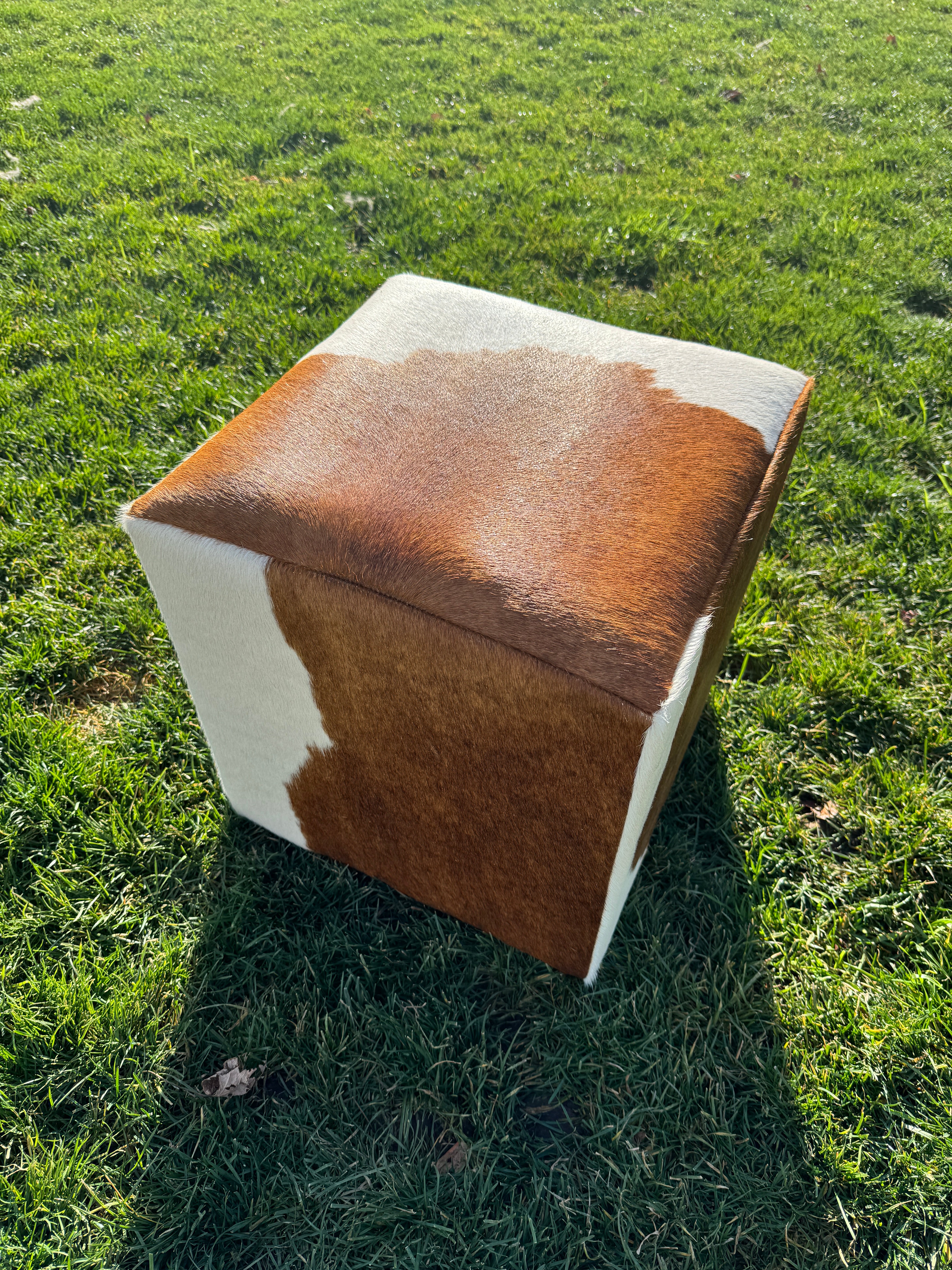 Brown and white cowhide cube ottoman on feet with natural hide pattern in Western rustic, yet elegant style
