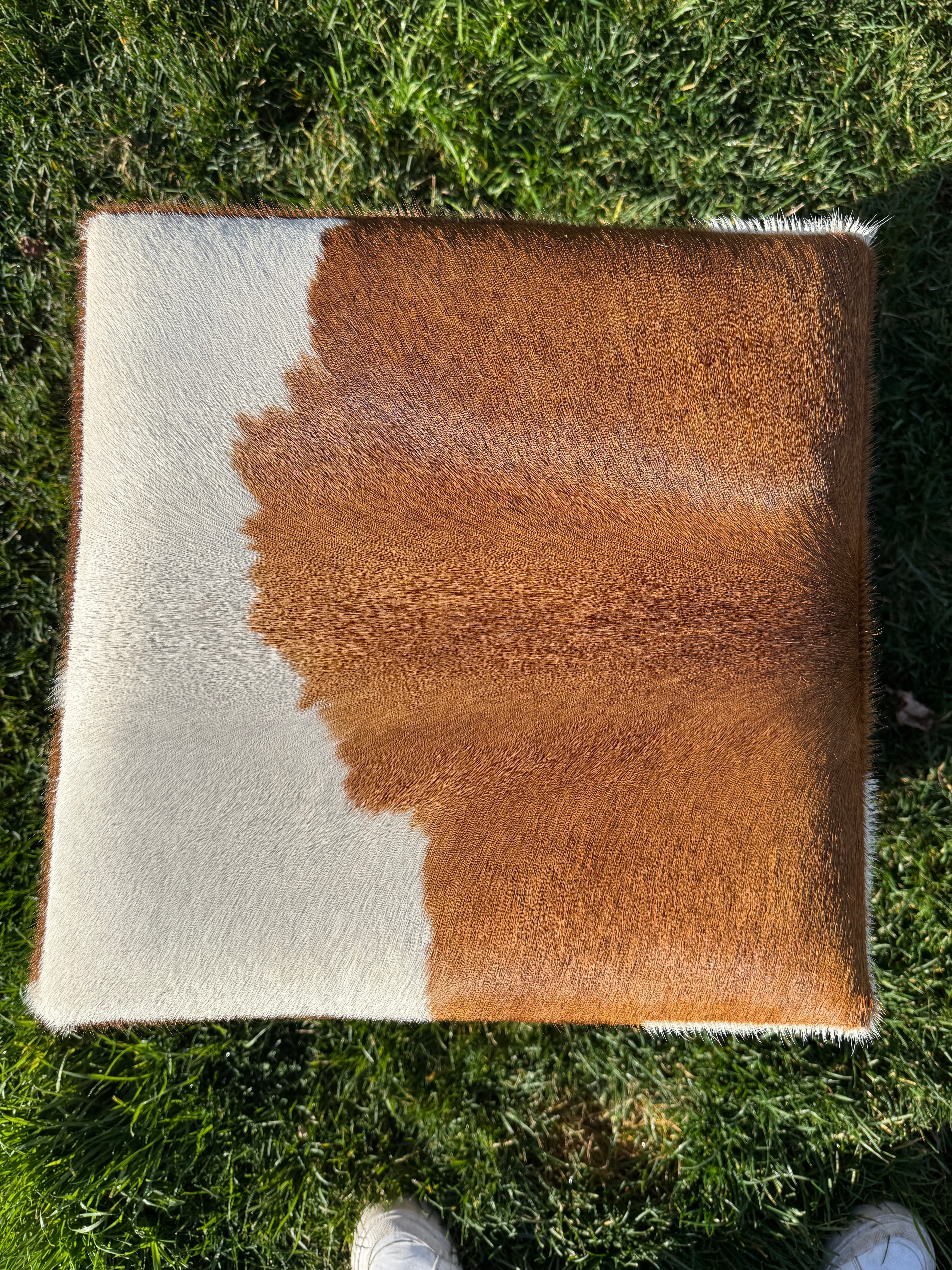 Brown and white cowhide cube ottoman top on feet with natural hide pattern in Western rustic, yet elegant style