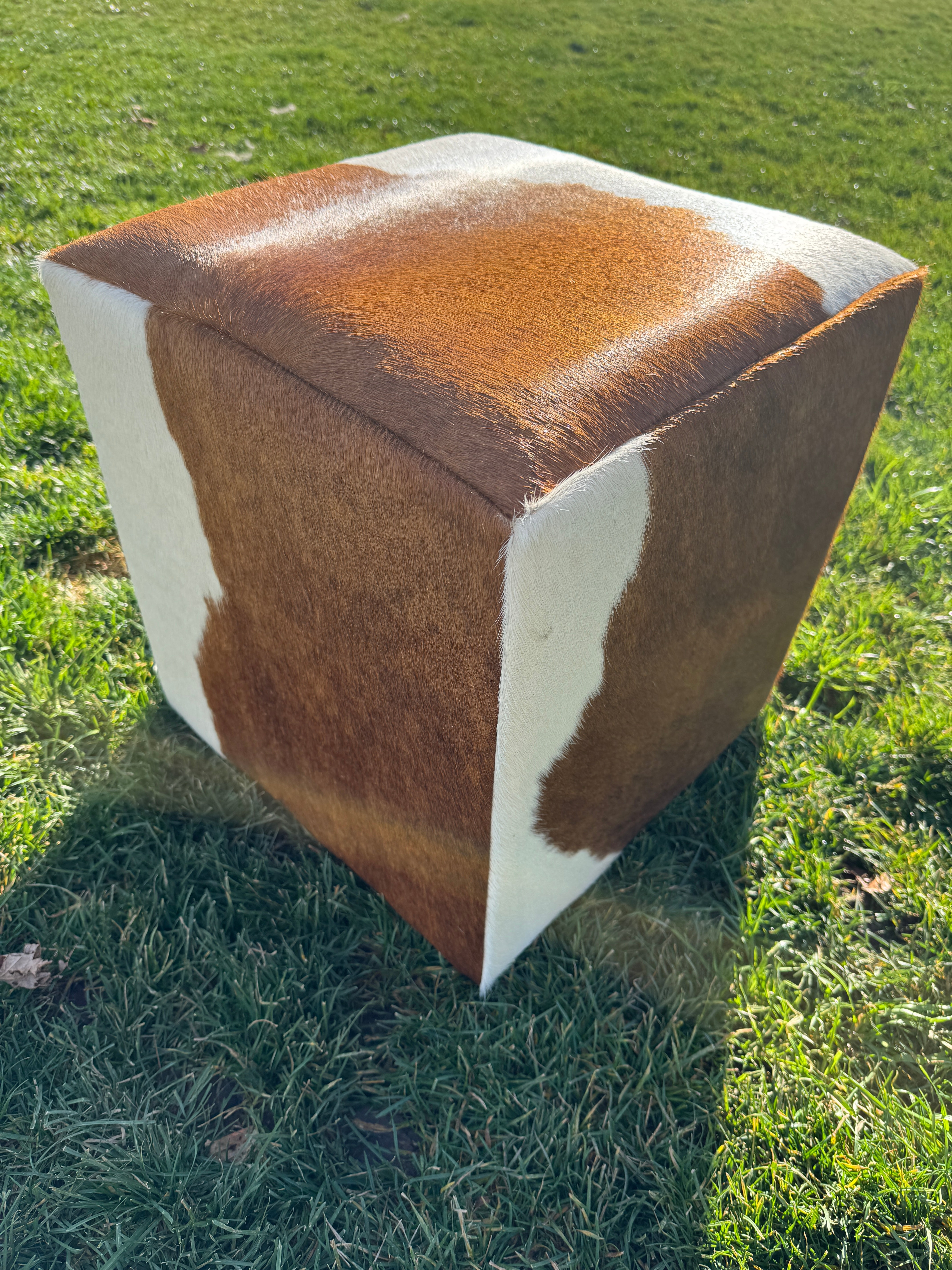 Brown and white cowhide cube ottoman on feet with natural hide pattern in Western rustic, yet elegant style