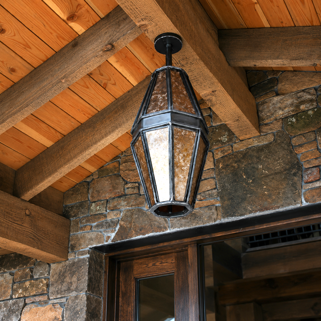 Hand forged rustic Mountain Ridge Mica and Iron Pendant Light with silver mich hanging on a lodge porch ceiling