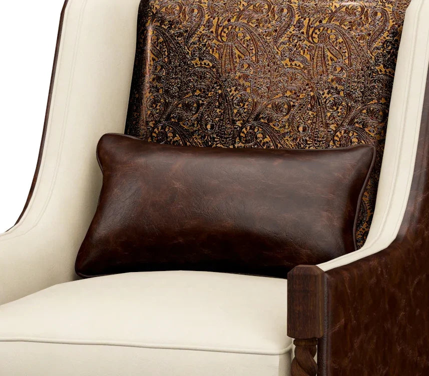 Brown leather pillow on a white armchair with a patterned brown backrest.