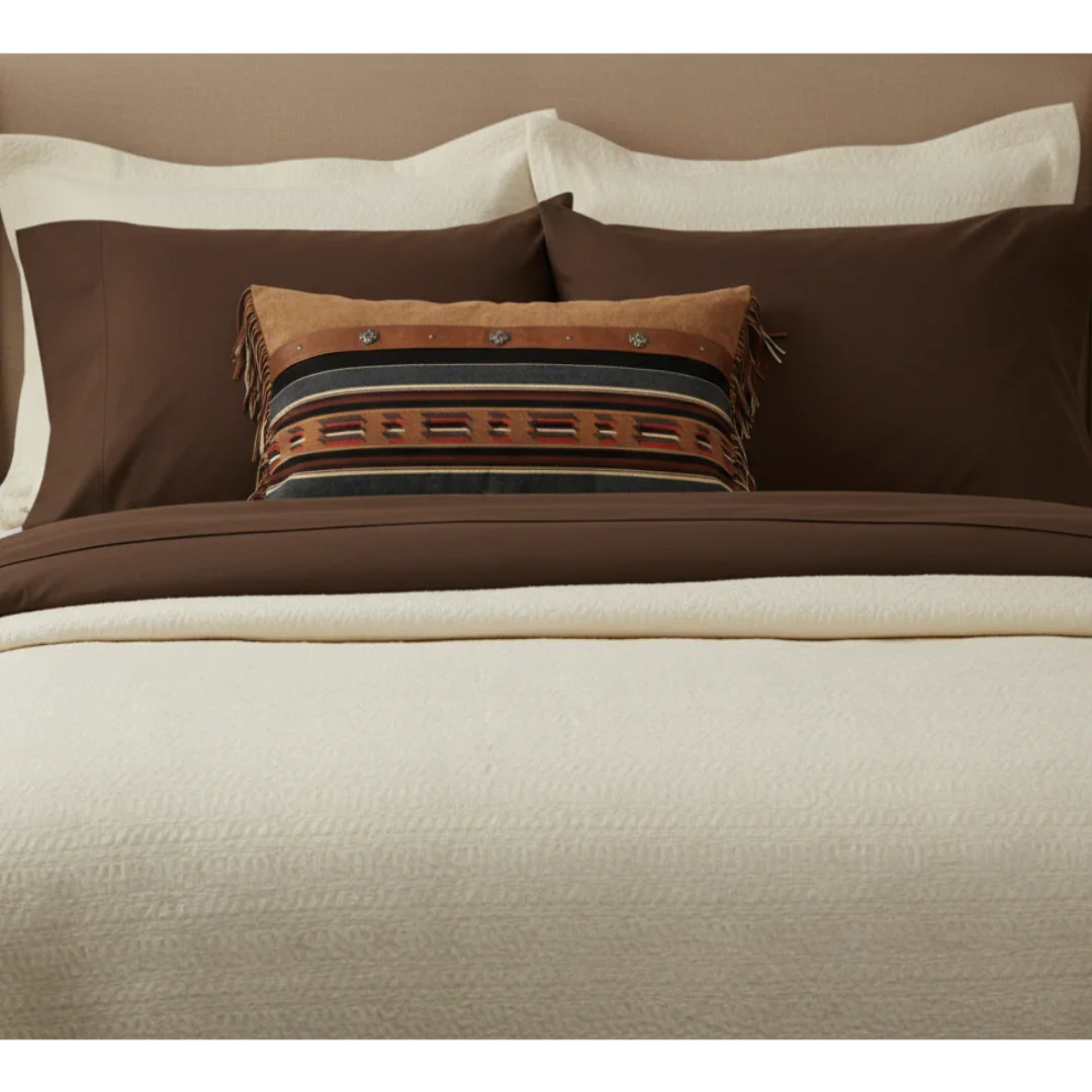 Brown and beige bedding set with decorative pillows on a bed.