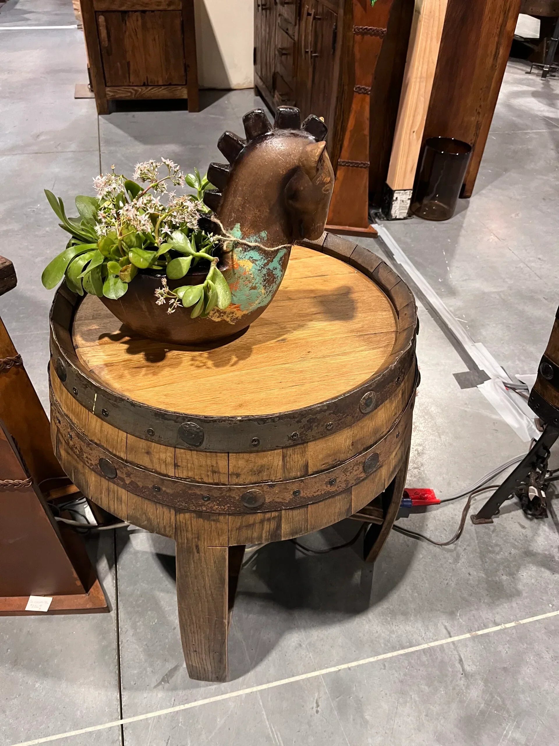 Decorative table with horse sculpture and plant on a wooden barrel base in an indoor setting - Your Western Decor