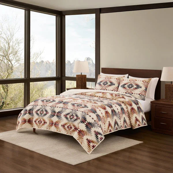 Bedroom with a bed featuring a patterned comforter and pillows, surrounded by large windows.