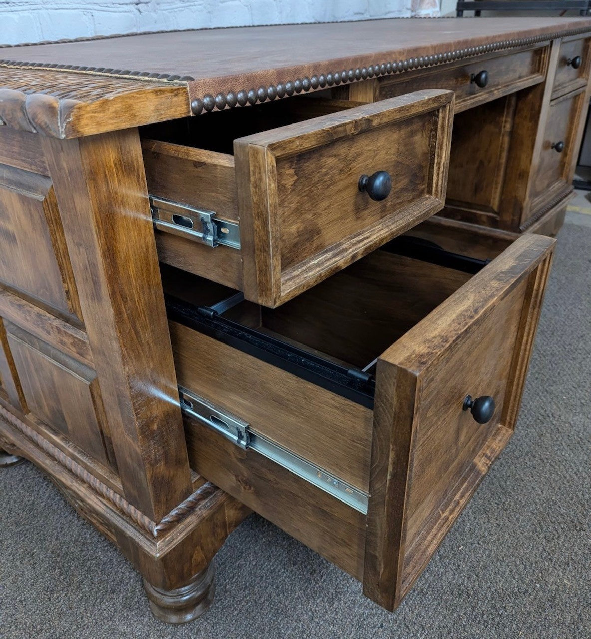 Alder wood desk with open drawers on a carpeted floor