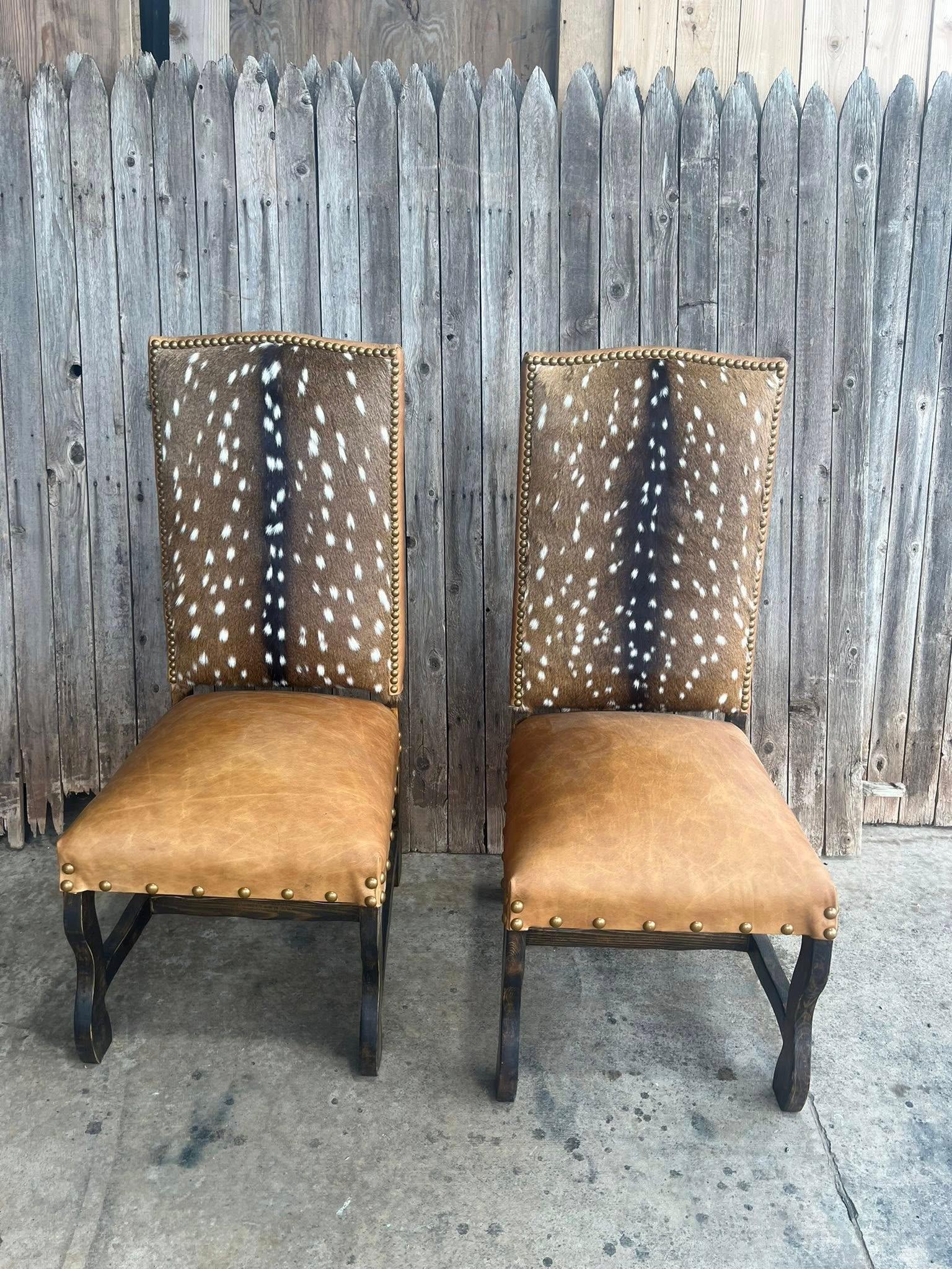 Two chairs with deer skin patterned backs and brown cushioned seats against a wooden fence - Your Western Decor