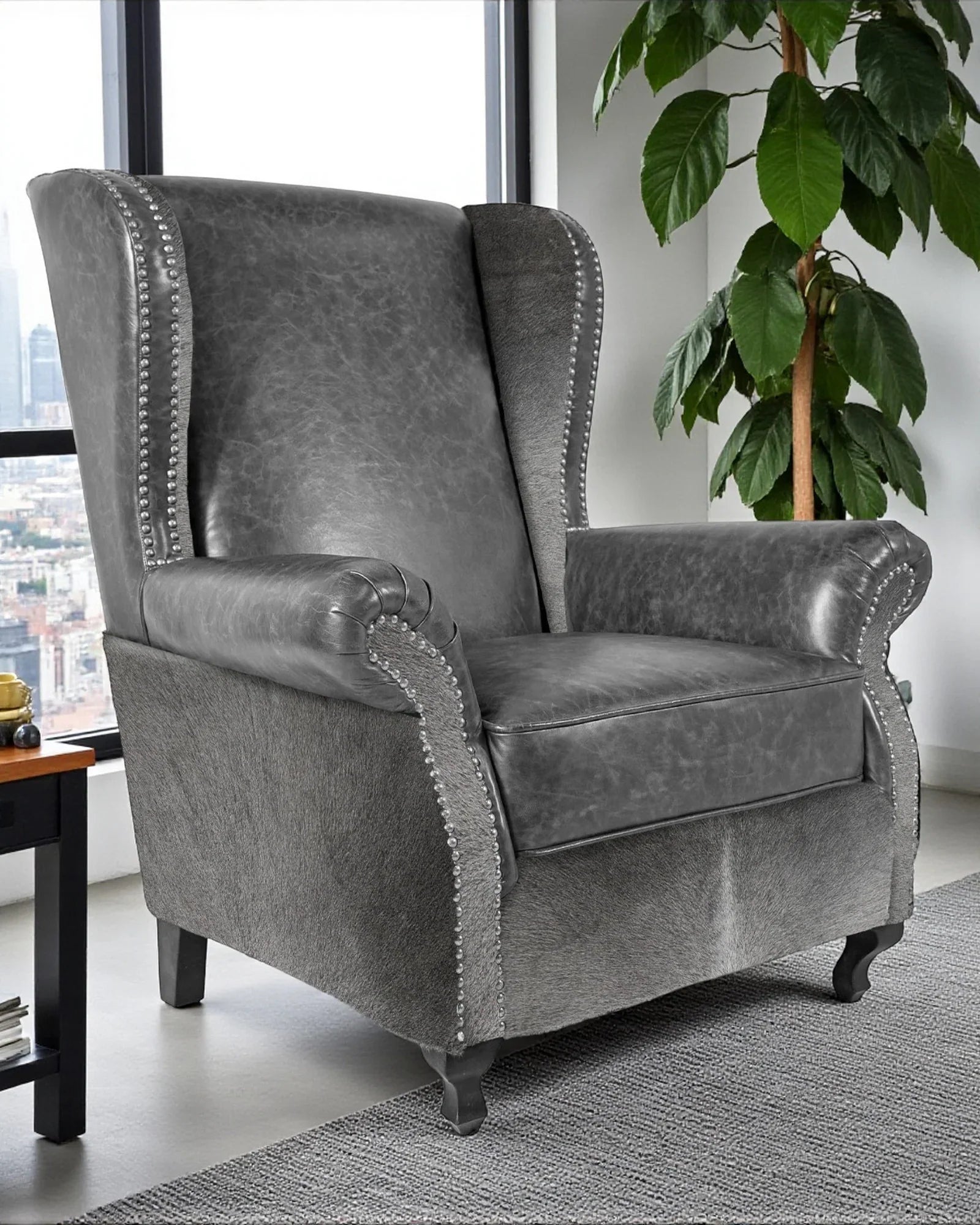 Gray armchair with nailhead trim in a room with a city view and a plant - Your Western Decor
