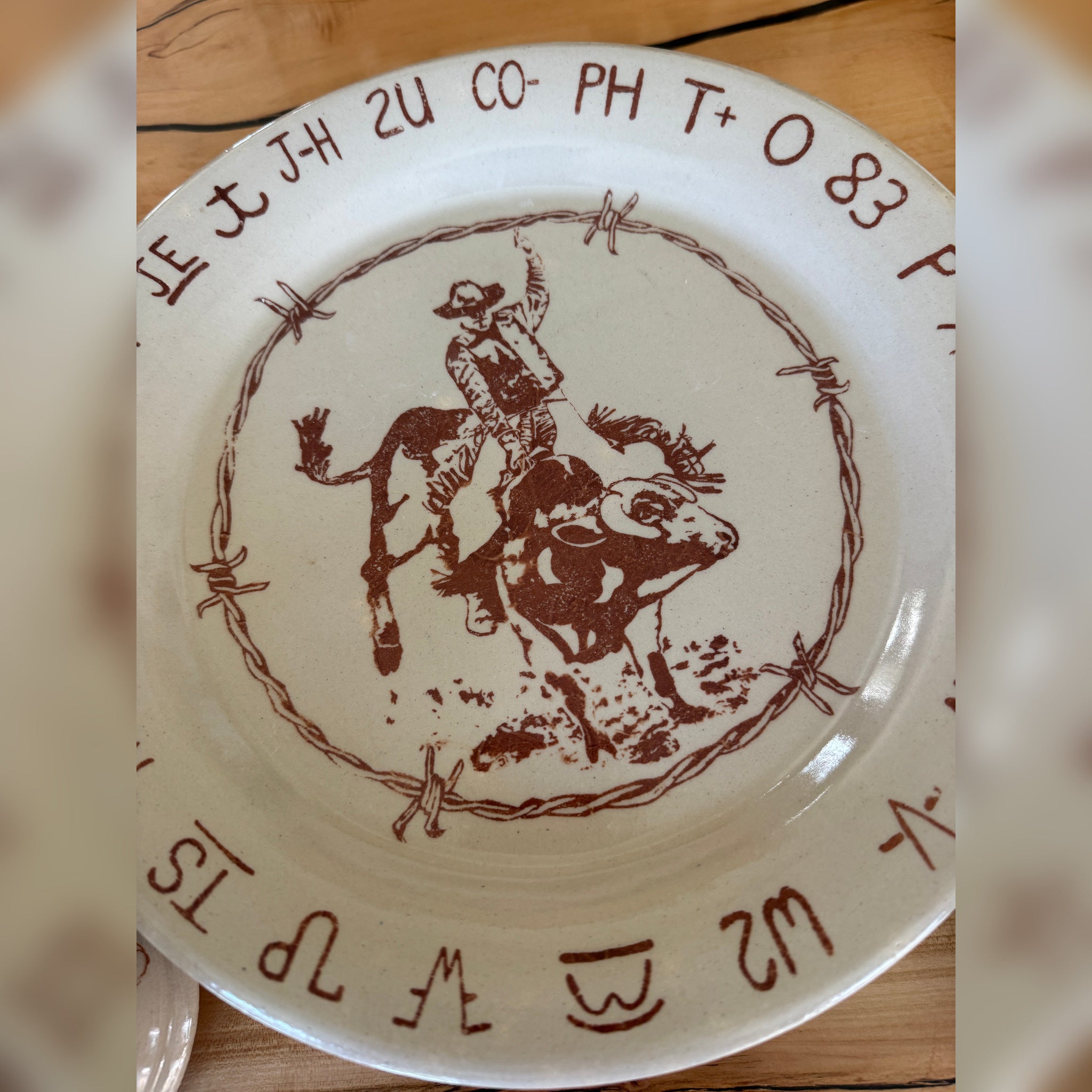 Blue Mountain Brands western dinner plate handmade in Pendleton, Oregon featuring Pendleton Round Up bull rider, barbed wire, Oregon ranch brands in dark brown over warm ivory
