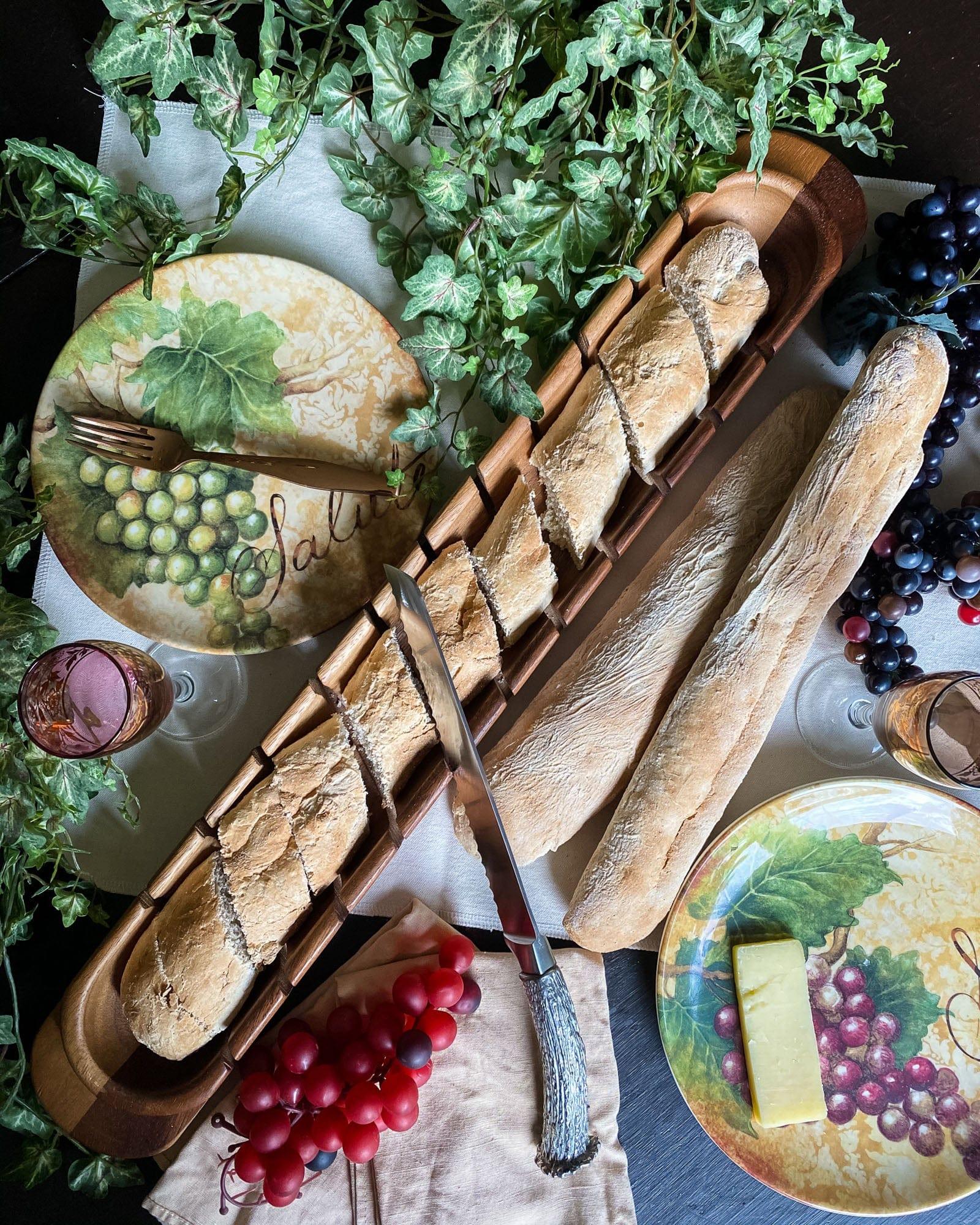 Bread display with decorative plates featuring grapes and a fork, surrounded by greenery and fruits - Your Western Decor