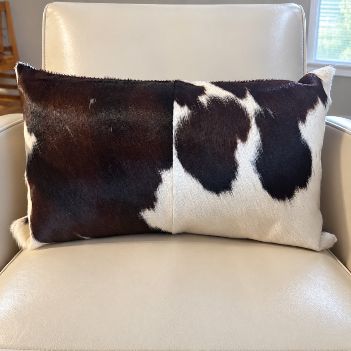 Chocolate and white genuine cowhide lumbar throw pillow with reversible seamed panel design
