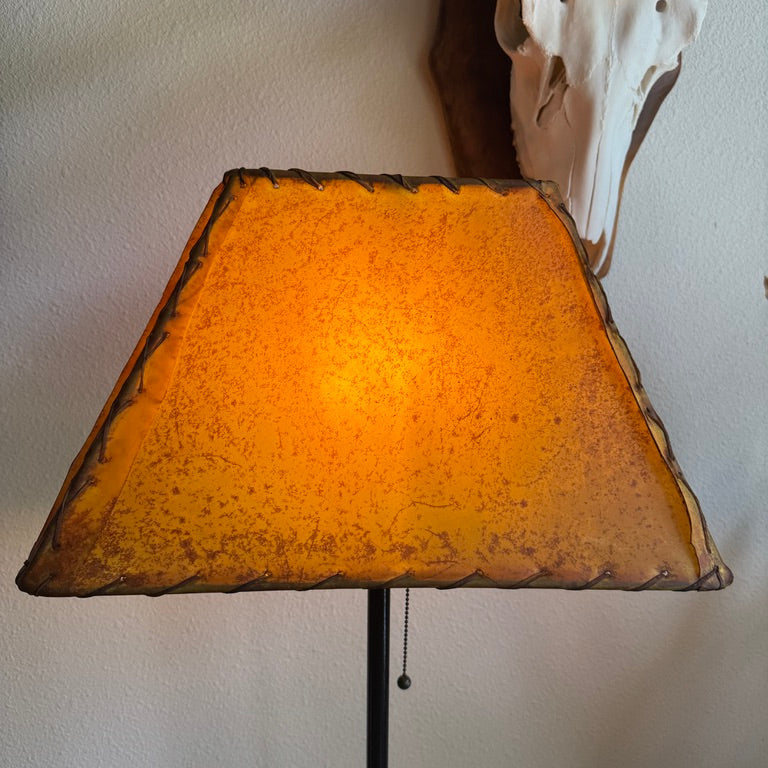 Buckskin rawhide lamp shade glowing warm amber light with authentic natural rawhide character