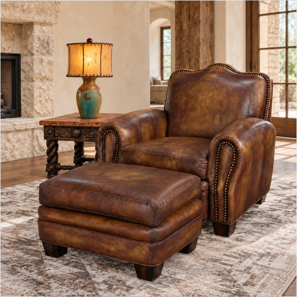 A brown leather armchair with matching ottoman in a rustic living room setting, next to a wooden side table with a lit lamp.