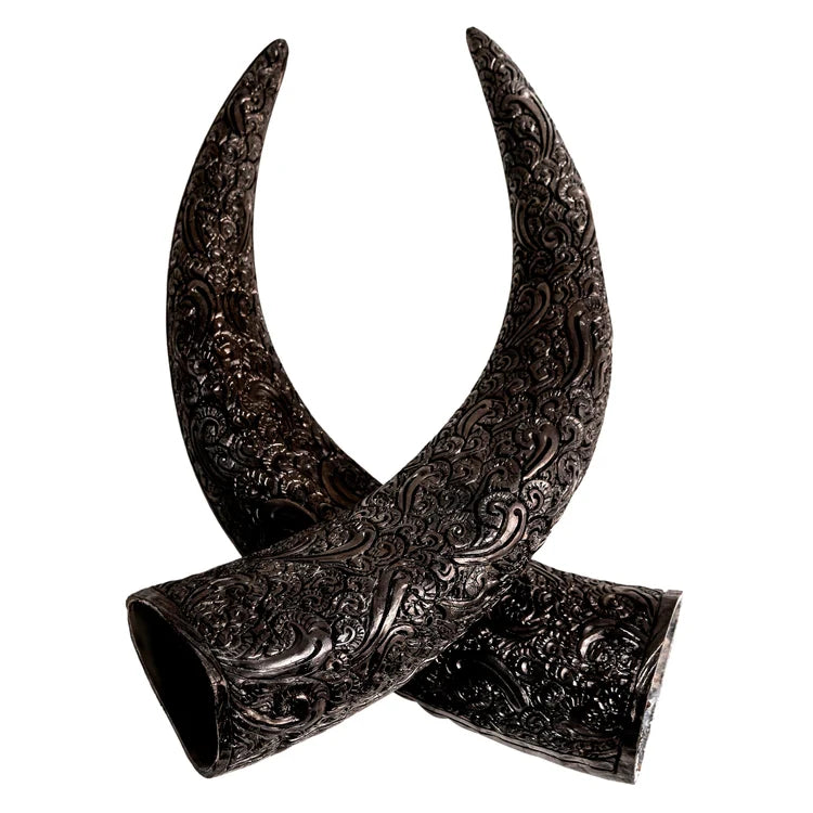 Two dark carved steer horn accessories with intricate embossed scrollwork, crossed over each other on a plain white background.