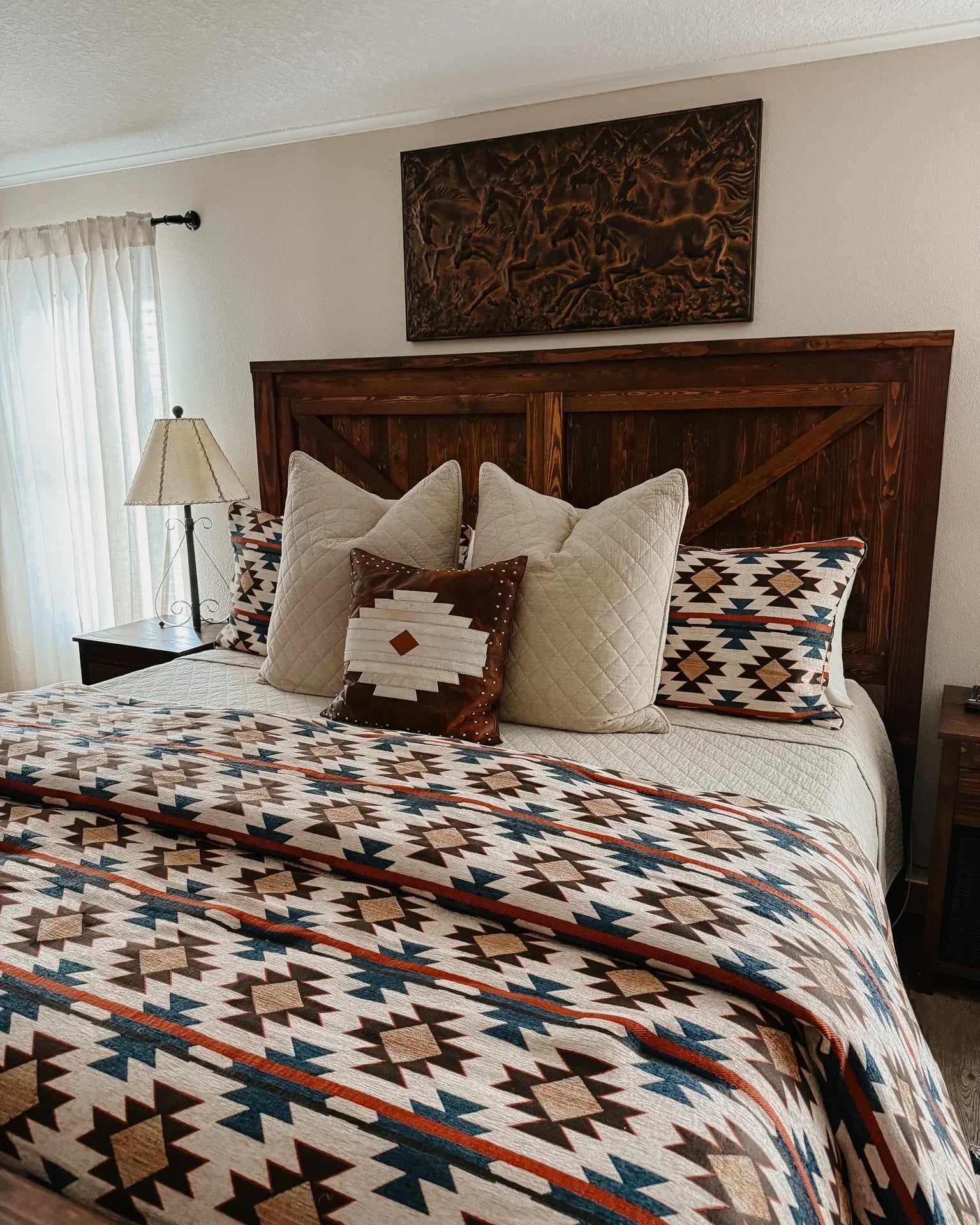 Bedroom with wooden headboard, patterned bedding, and decorative pillows - Your Western Decor