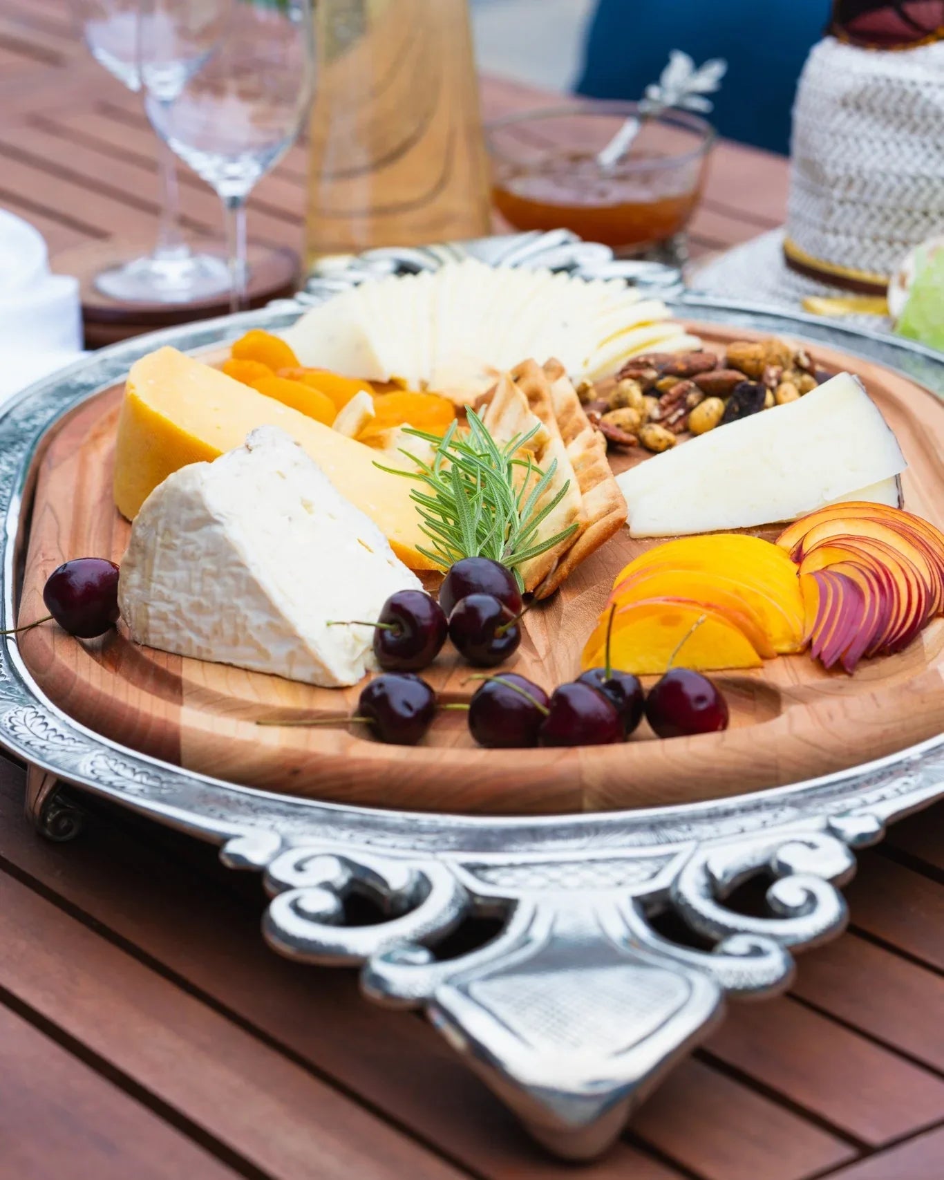 Wooden cheese board with assorted cheeses, fruits, and nuts on a wooden table - Your Western Decor