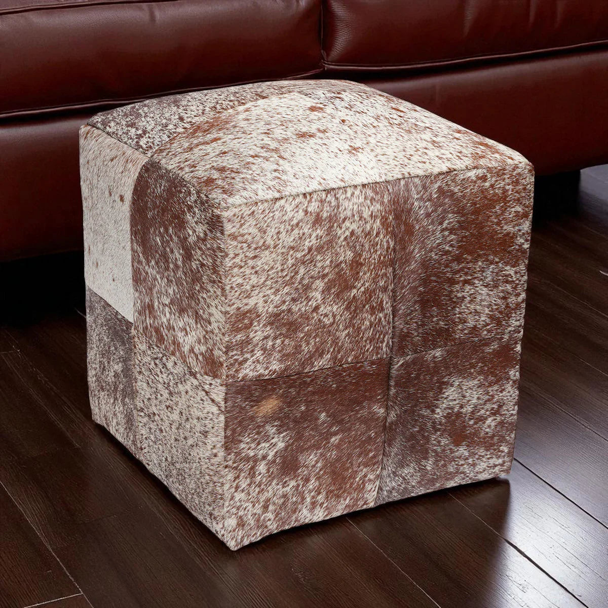 Cube-shaped ottoman with brown and white patchwork design on a wooden floor - Your Western Decor