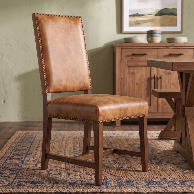 Tan leather dining chair with brown wood frame and nail trim
