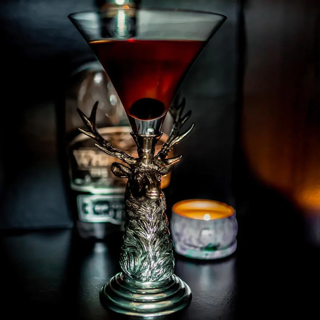 Cocktail in a decorative glass with elk base on a dark background - Your Western Decor