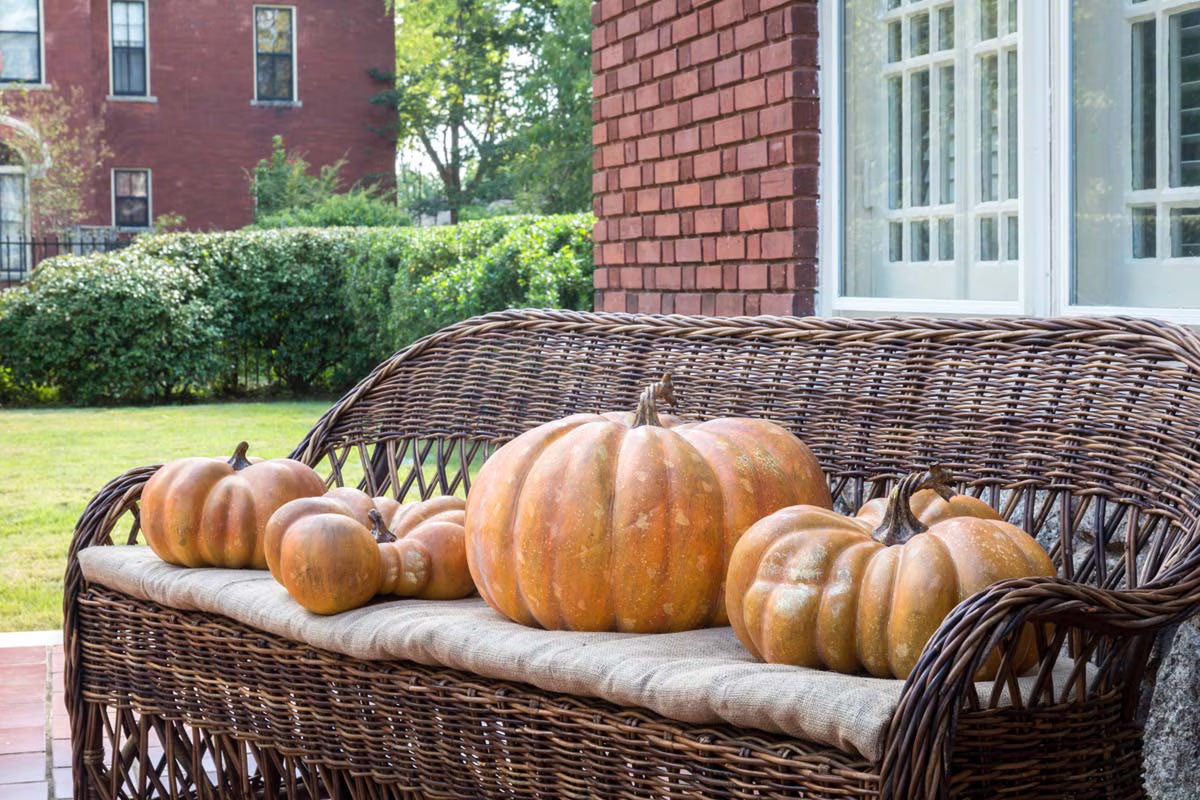 Pumpkins on a wicker bench in front of a house - Your Western Decor