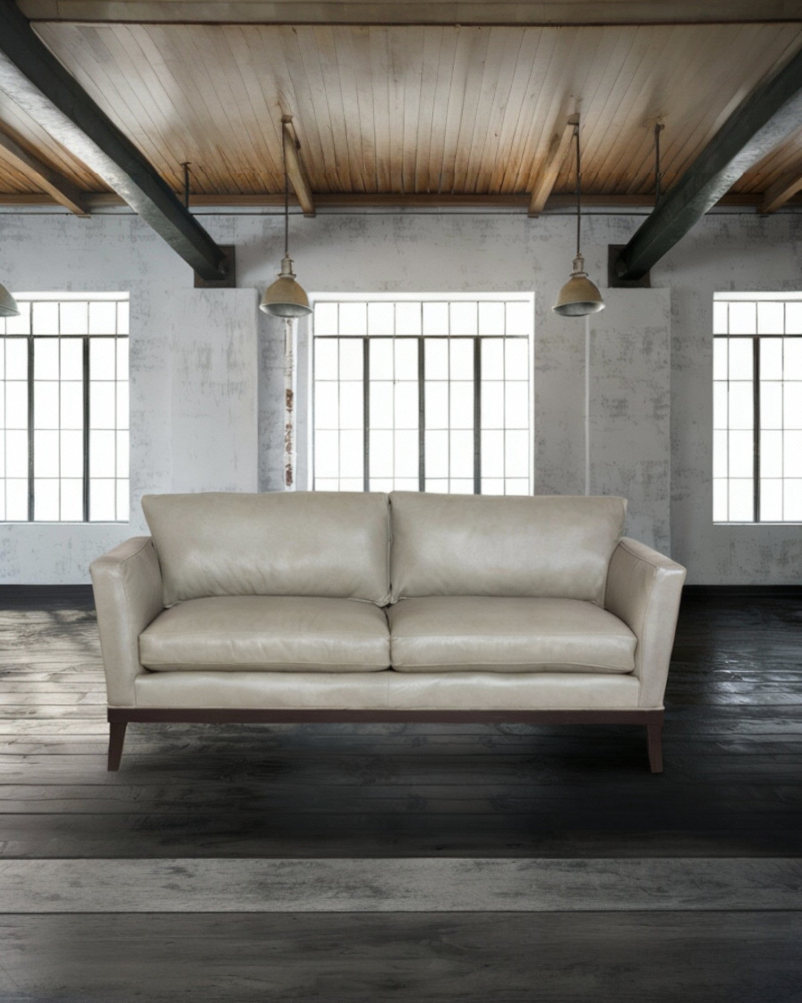 Grey leather sofa in a room with exposed wooden beams and large windows - Your Western Decor