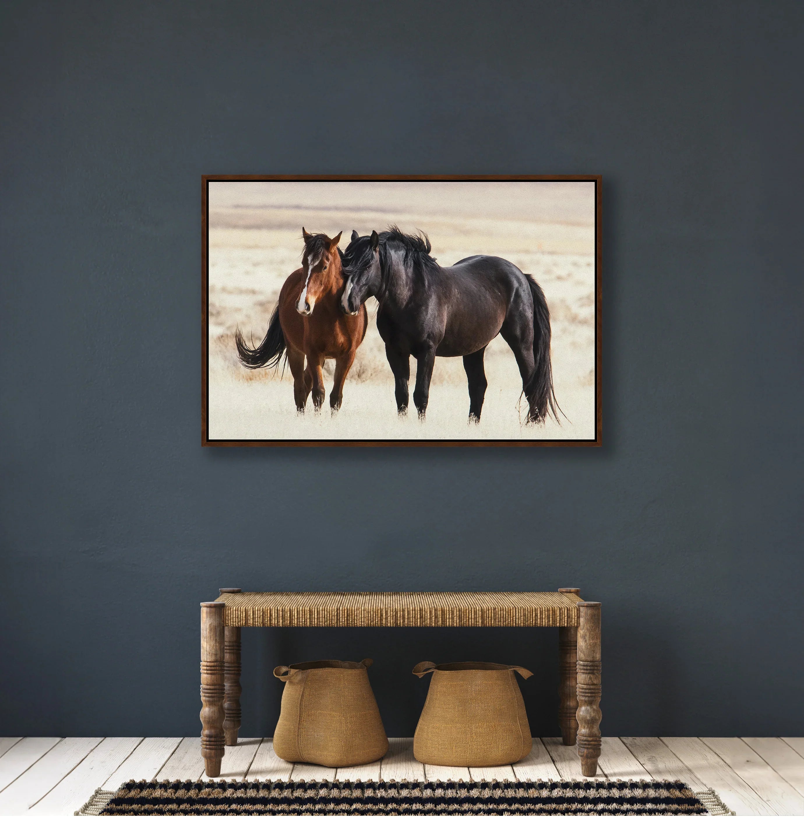 Framed artwork of two horses on a dark blue wall above a wooden console table - Your Western Decor