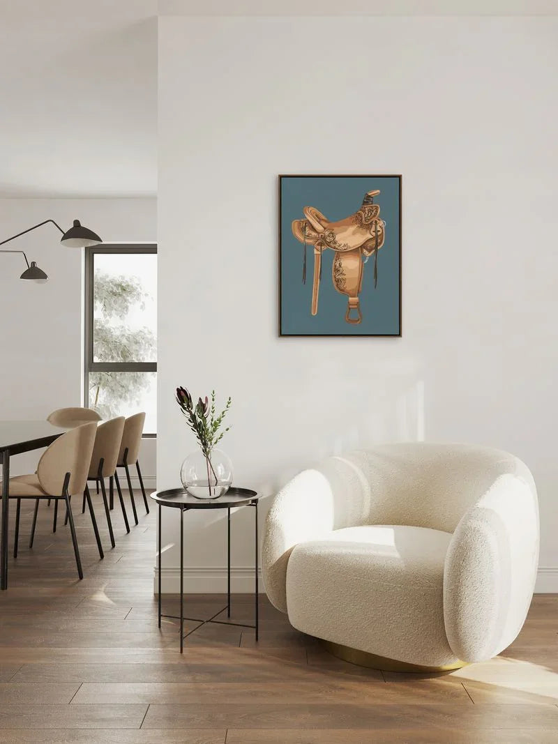 Modern living room with a white armchair, dining table, and wall art of a western saddle - Your Western Decor