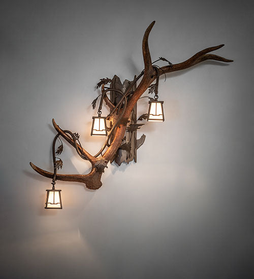 Left facing elk and mule deer antler wall sconce with three lantern lights for rustic lodge style, handcrafted in the USA