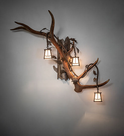 Right facing elk and mule deer antler wall sconce with three lantern lights in rustic lodge style, handcrafted in the USA