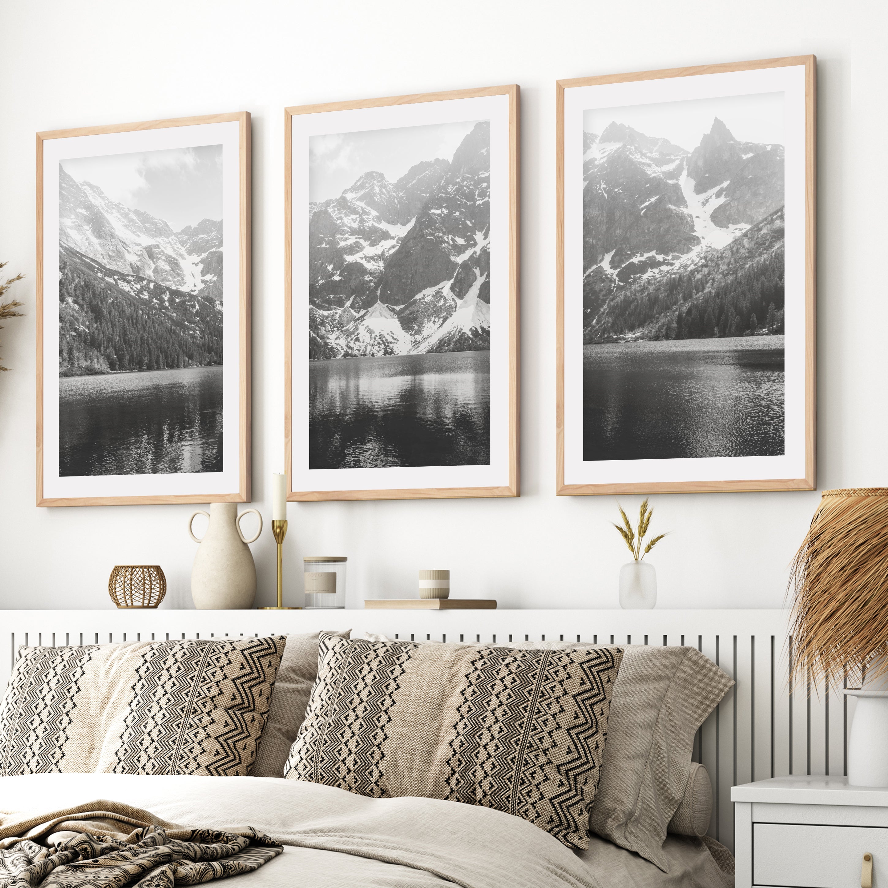 Three framed black and white mountain landscape prints above a bed with natural wood frames and white border
