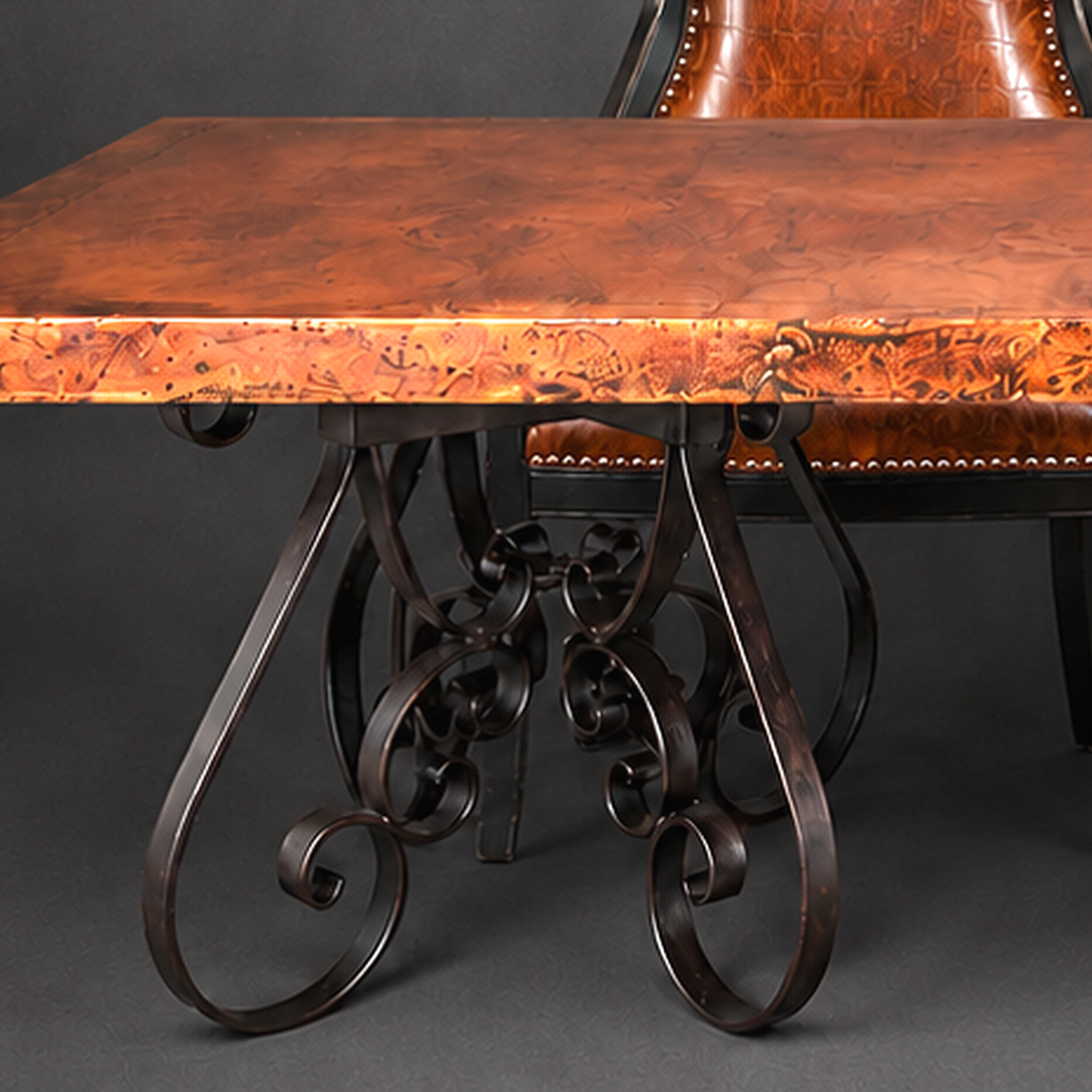 A close-up of an ornate dining table with a rich copper-brown wood top and dark wrought iron scrollwork legs, shown alongside a matching brown leather chair against a dark gray background.