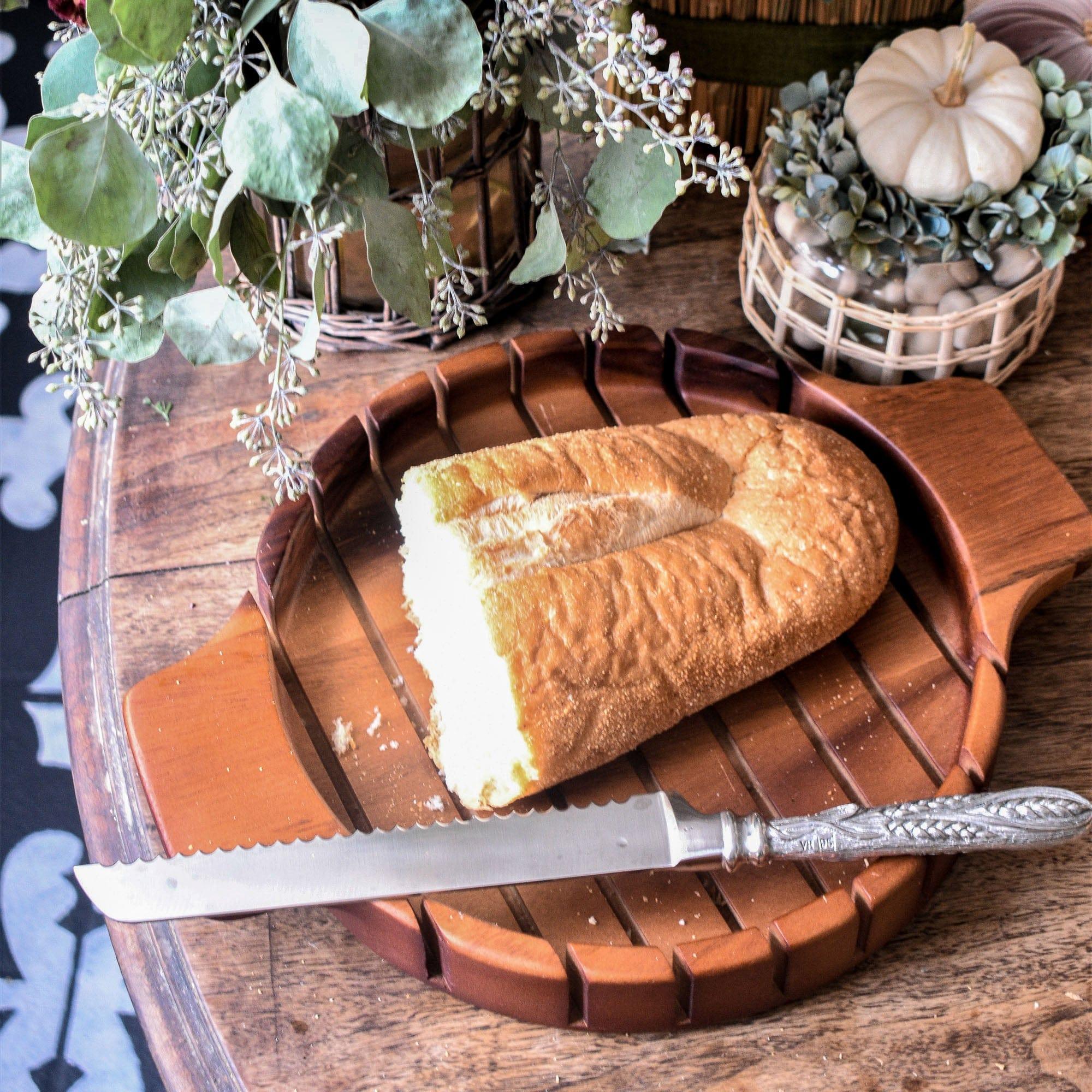 Loaf of bread on a wooden bread board with a knife, surrounded by decorative elements - Your Western Decor