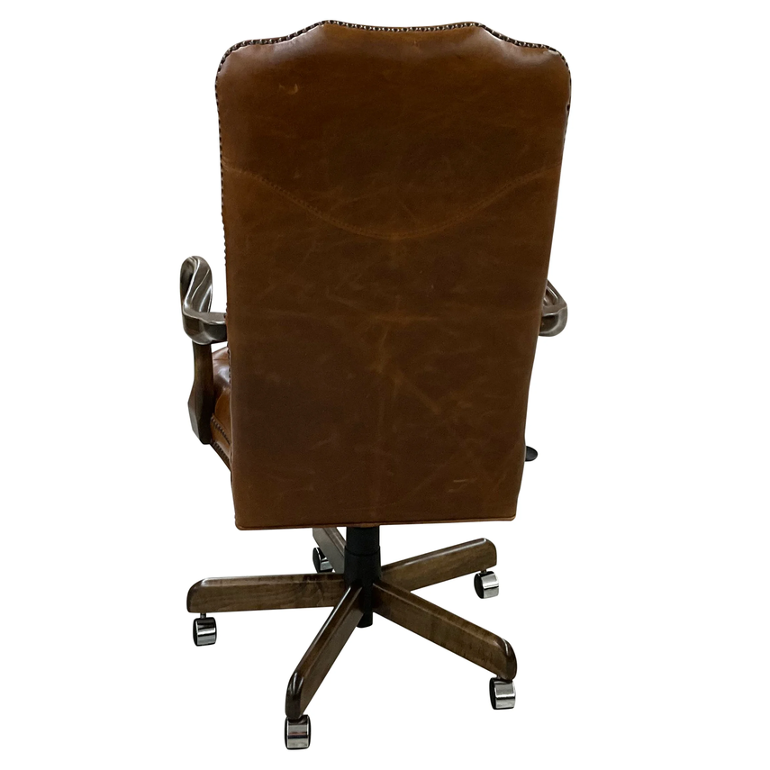 A brown leather office chair with a high back, nailhead trim, and a dark wood five-star wheeled base, shown from the rear against a white background.