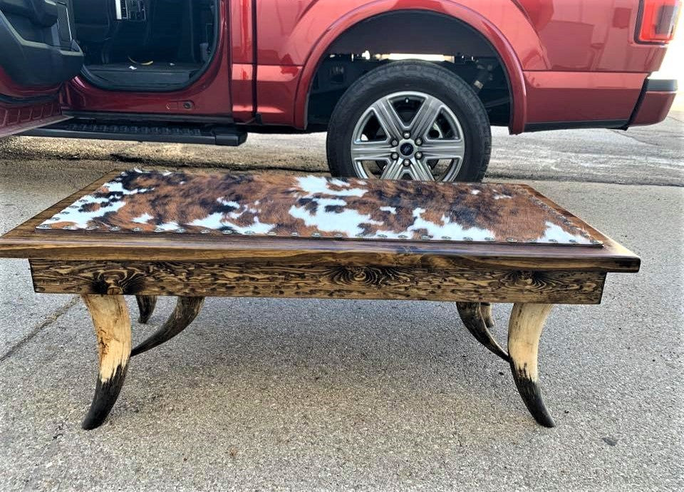 Custom made coffee table with steer horn legs, tri color cowhide surface, and nail trim