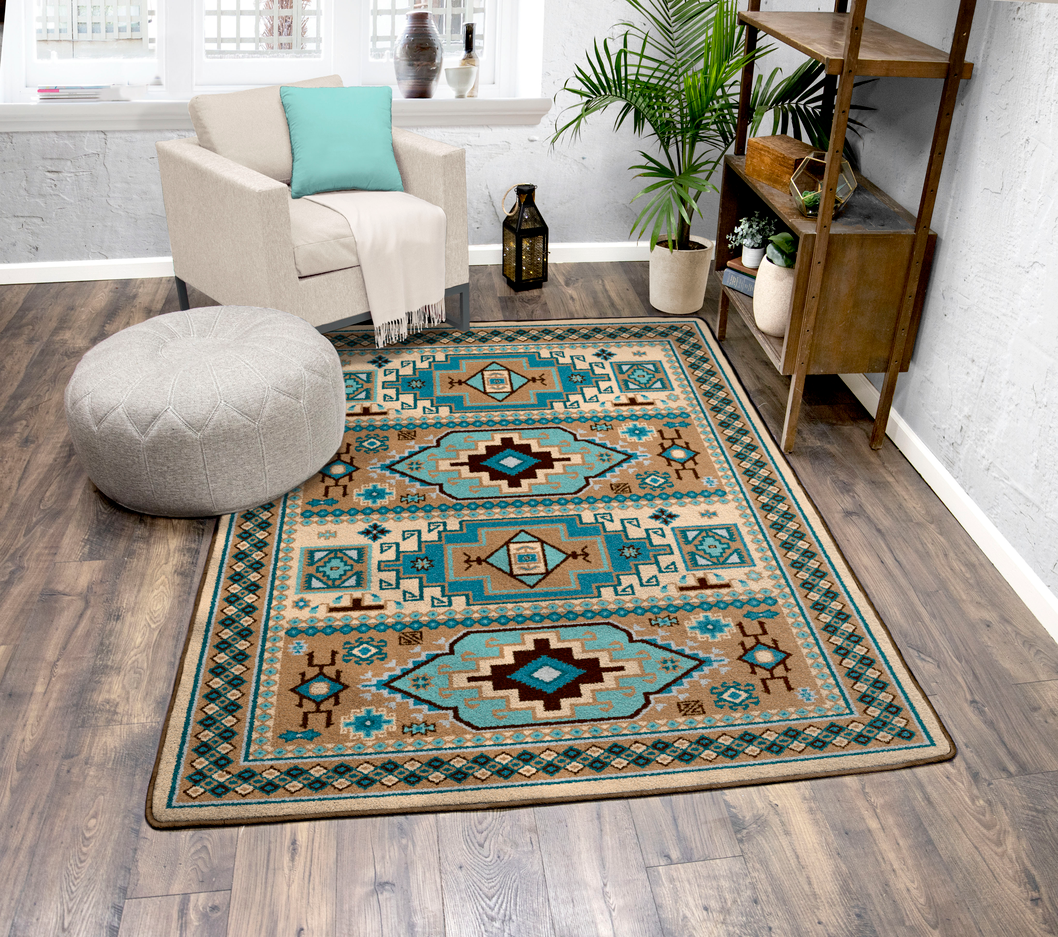 A rectangular area rug with a Southwestern geometric pattern in teal, beige, brown, and black, styled on a dark wood floor in a bright living room setting.