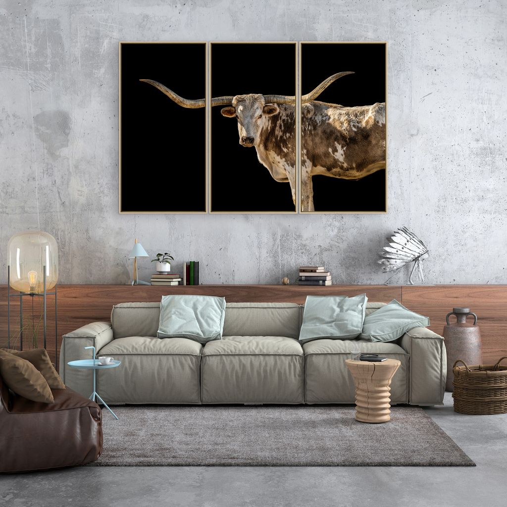 Living room with a large sofa, decorative pillows, and a triptych painting of a longhorn bull on the wall - Your Western Decor