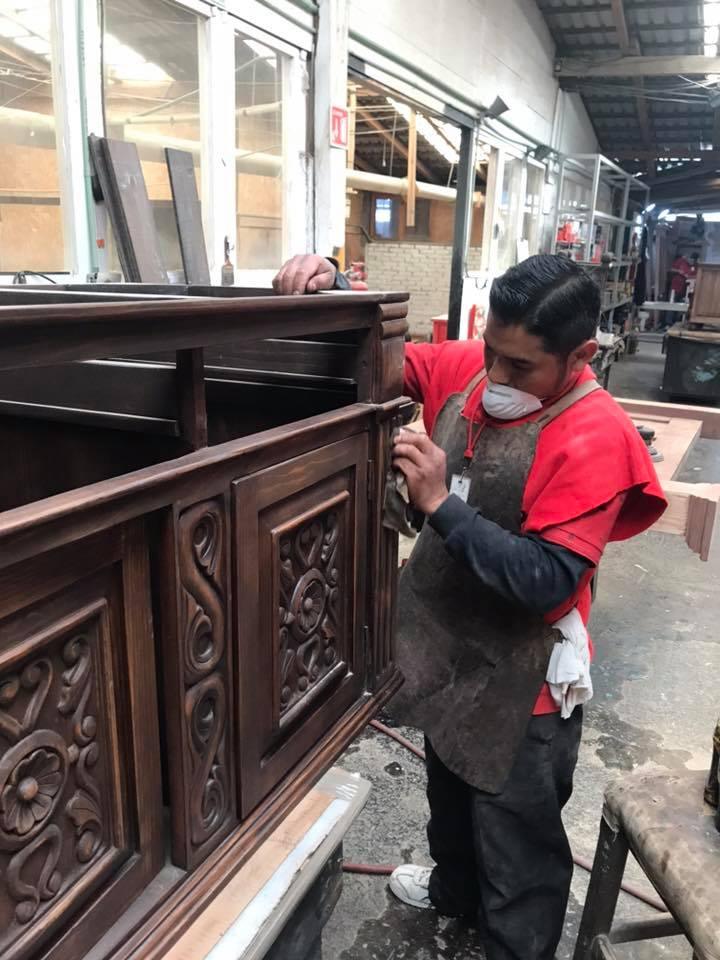 Person working on a wooden cabinet in a warehouse setting - Your Western Decor