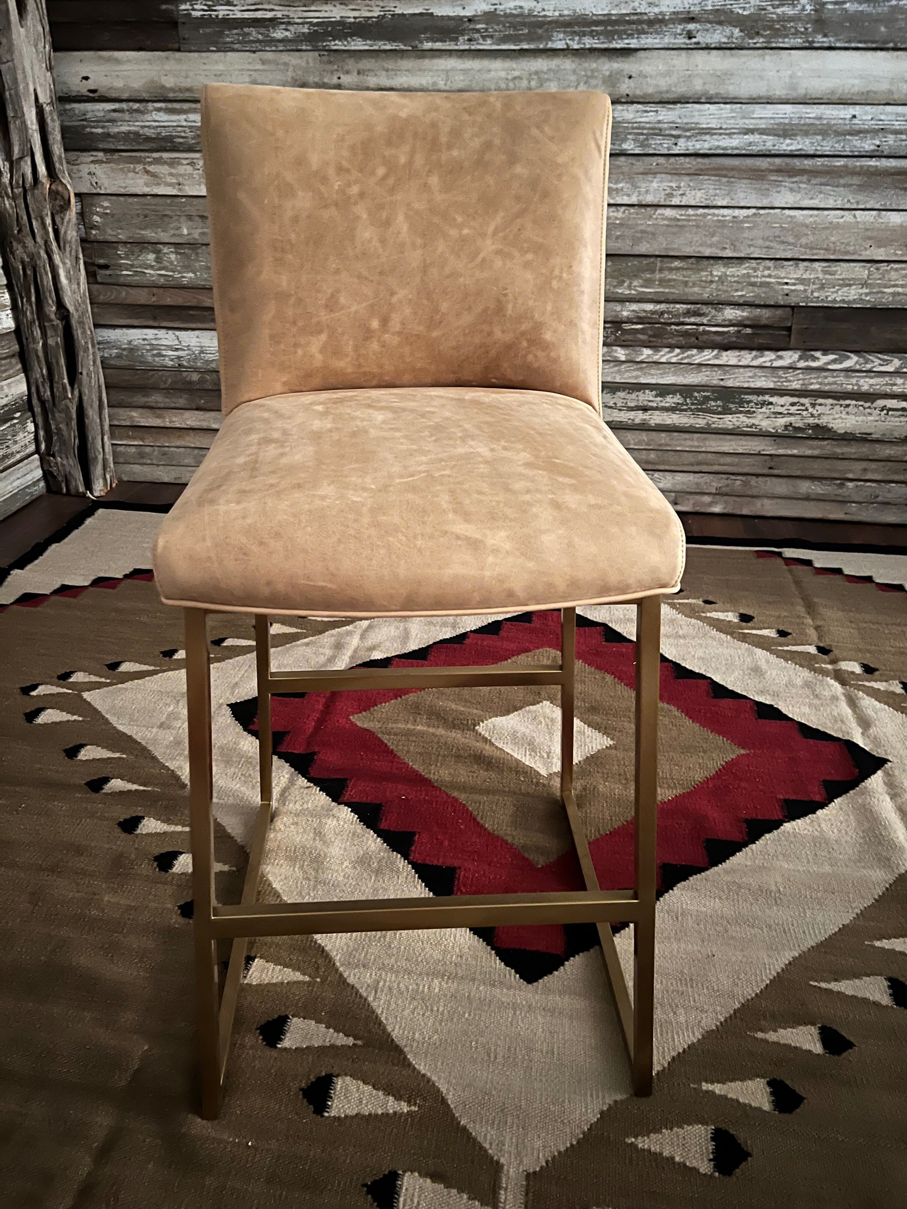 Beige leather bar stool against a rustic wooden wall with a patterned rug - Your Western Decor