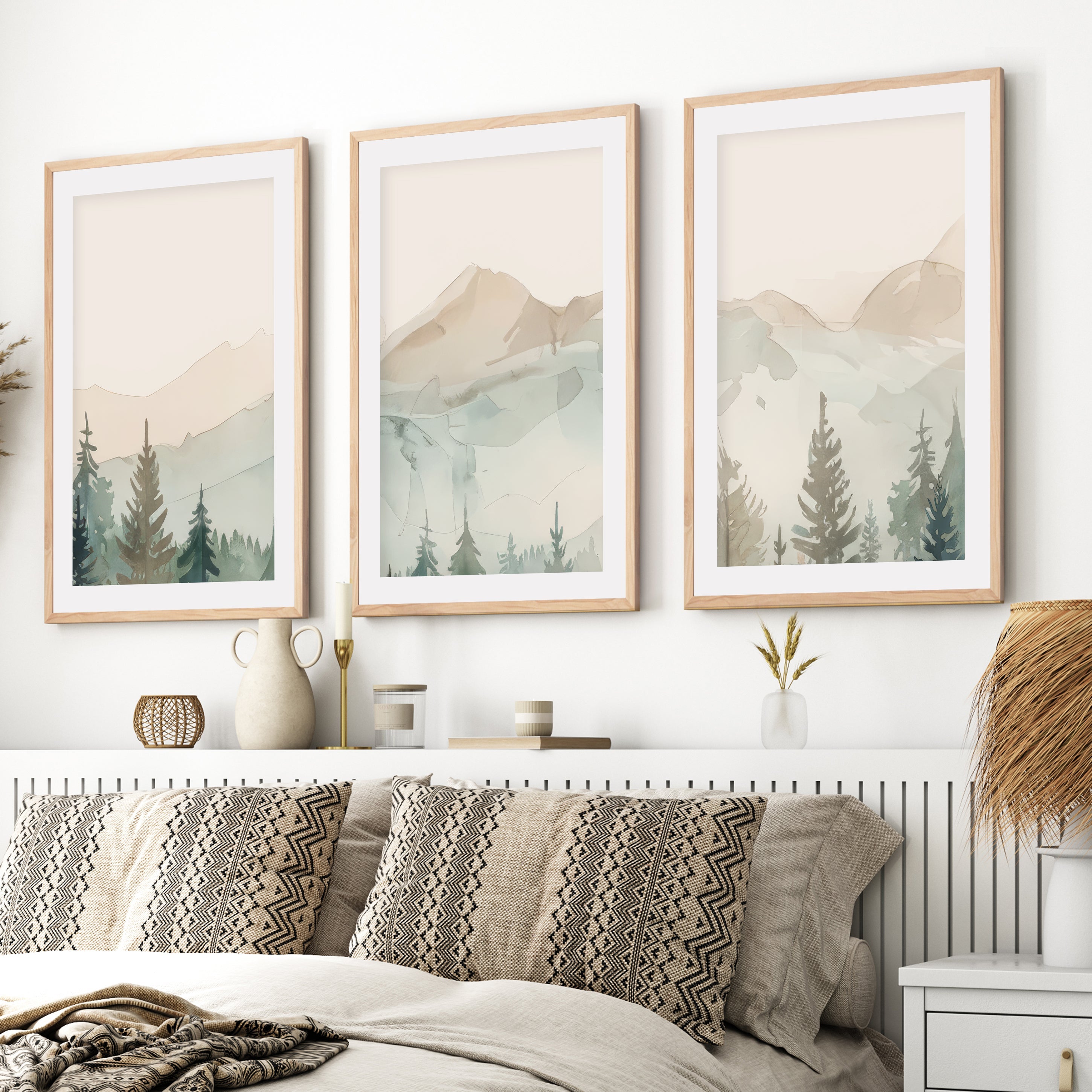 Watercolor triptych mountain scene art set with light wood frames and white border hanging above bed