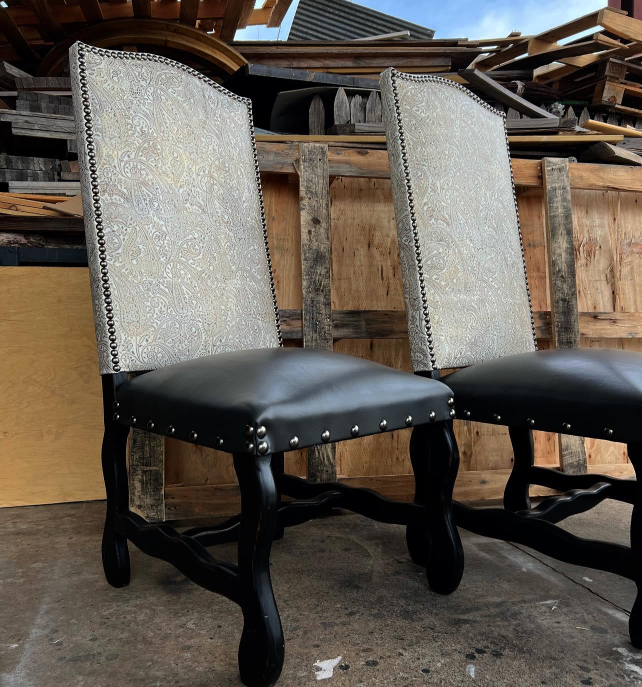 Two upholstered chairs with black seats and legs in front of a wooden pallet.