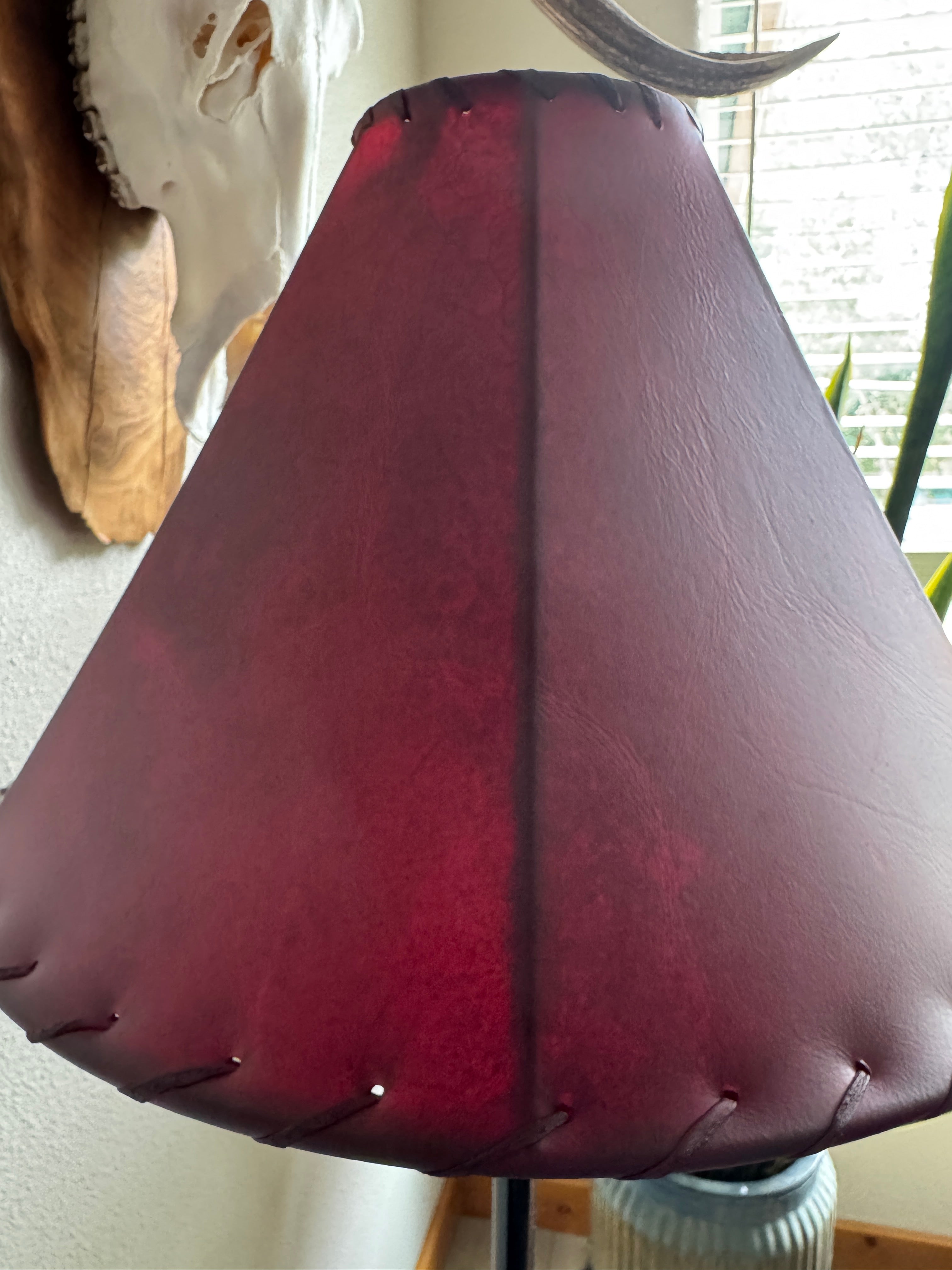 Red rawhide lamp shade in natural lighting with light off