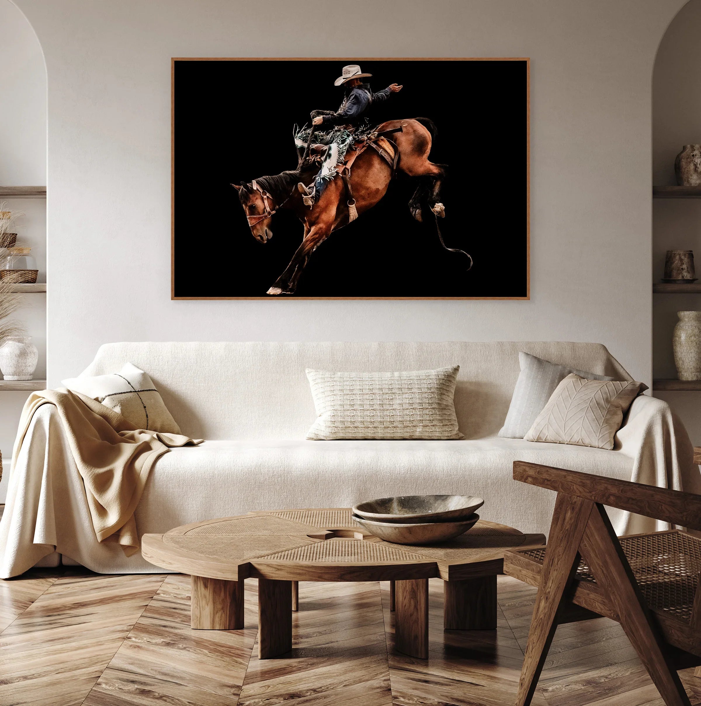 Living room with a framed picture of a cowboy on a bronc horse above a beige sofa - Your Western Decor