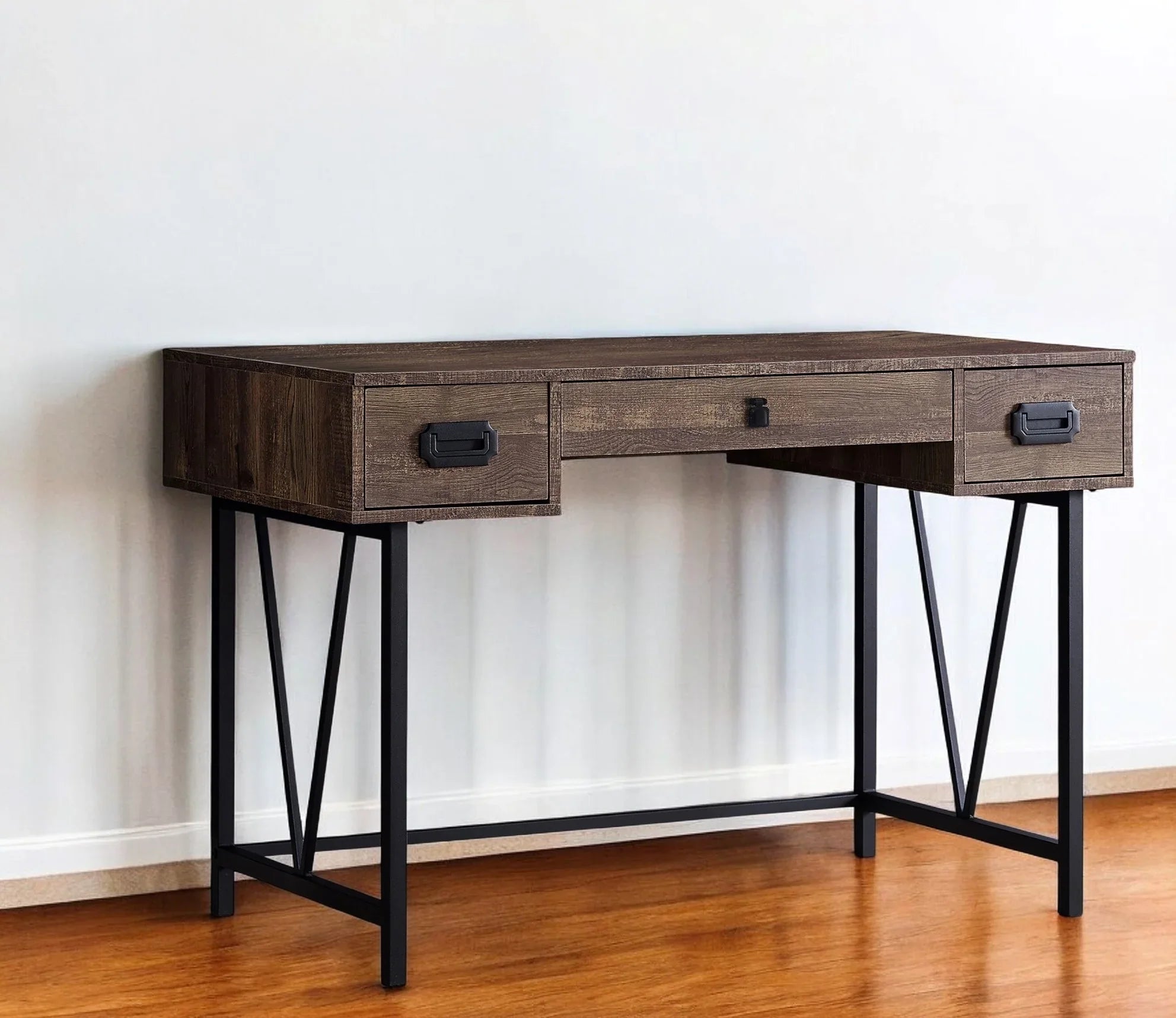 Wooden desk with black metal legs and wood top with 3 drawers against a white wall on a hardwood floor - Your Western Decor