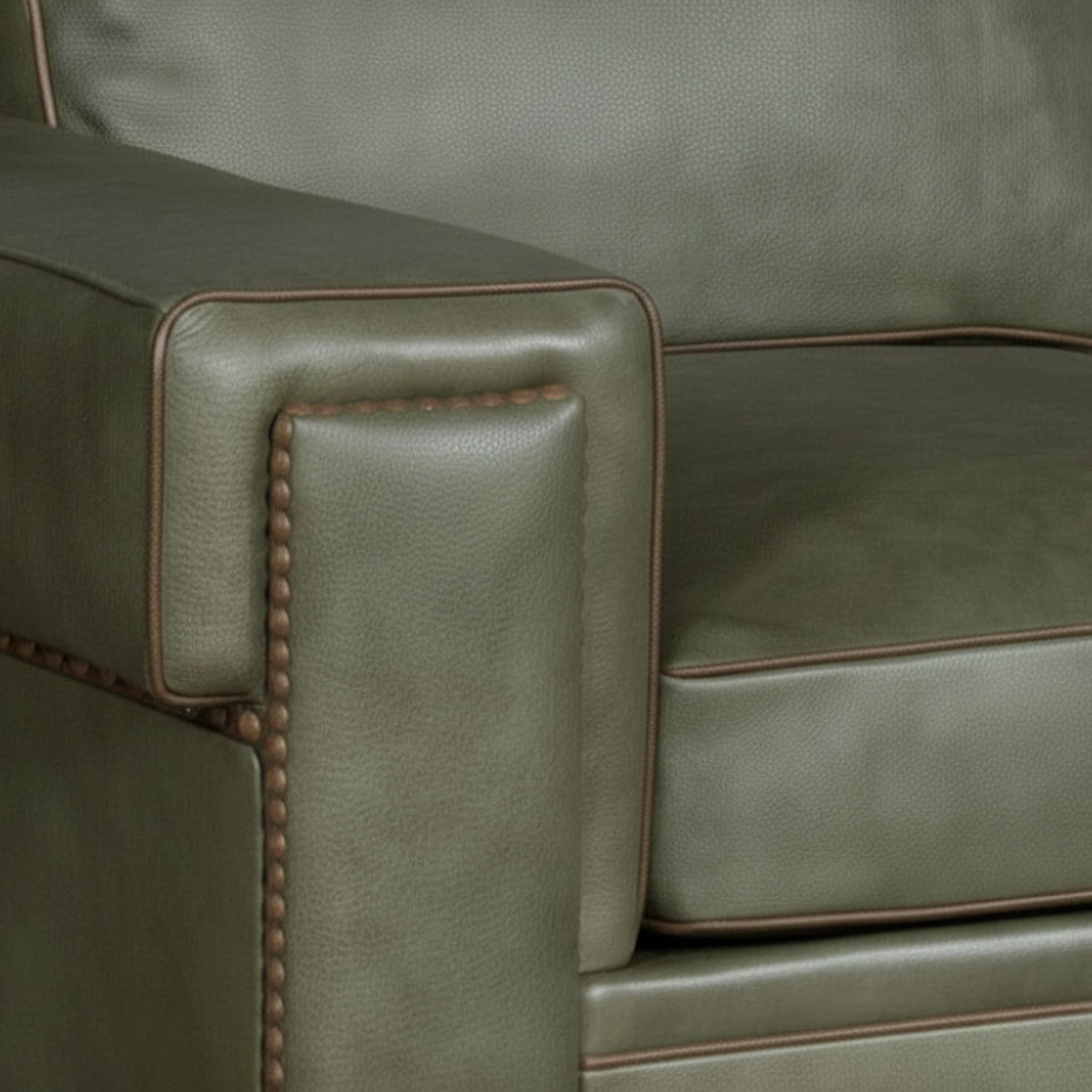 Close-up of a green leather sofa with brown nailhead trim