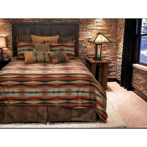 Bedroom with a bed featuring Sunset Canyon collection a patterned comforter and pillows, against a stone wall.
